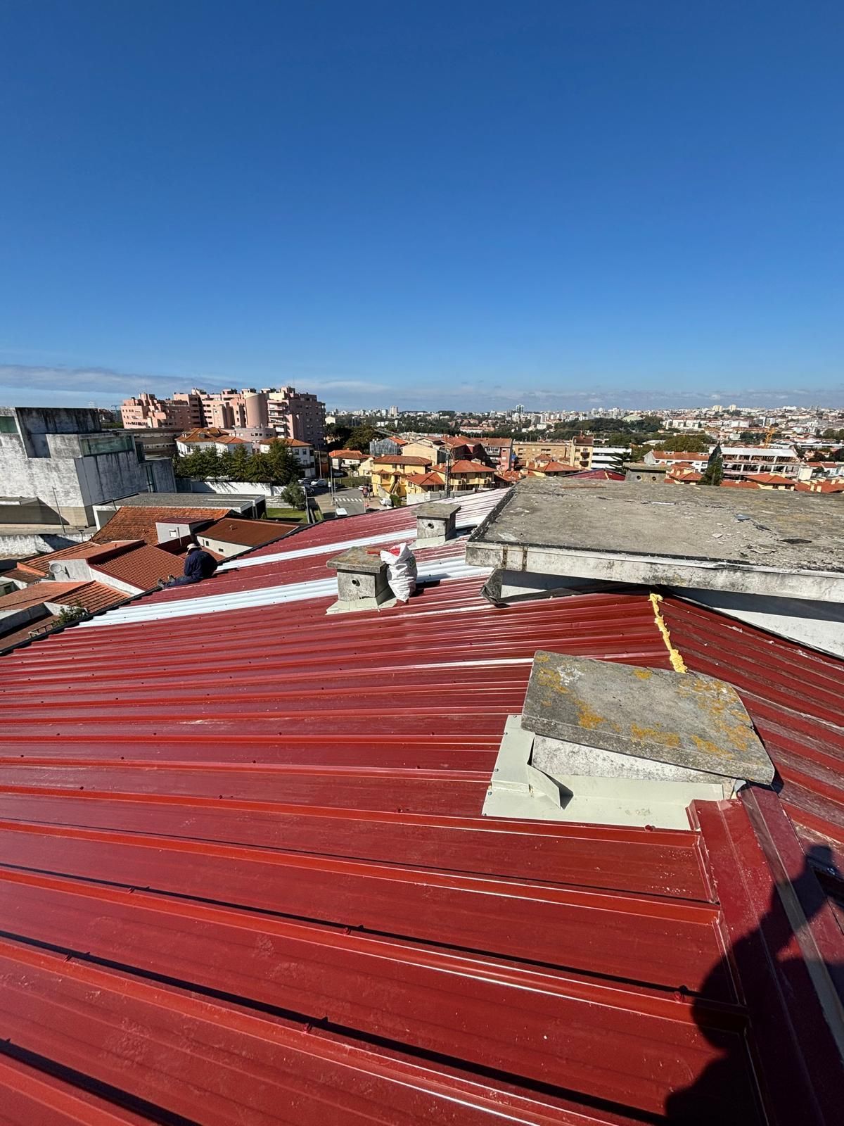 Um telhado vermelho em painel sandwich 5 ondas 30mmcom vista para uma cidade ao fundo.