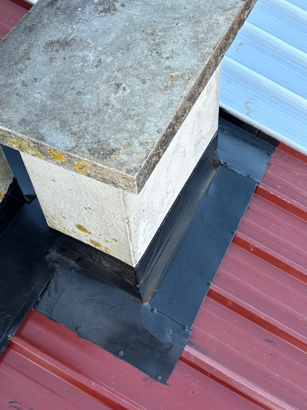 Uma chaminé está sobre um telhado de metal vermelho.