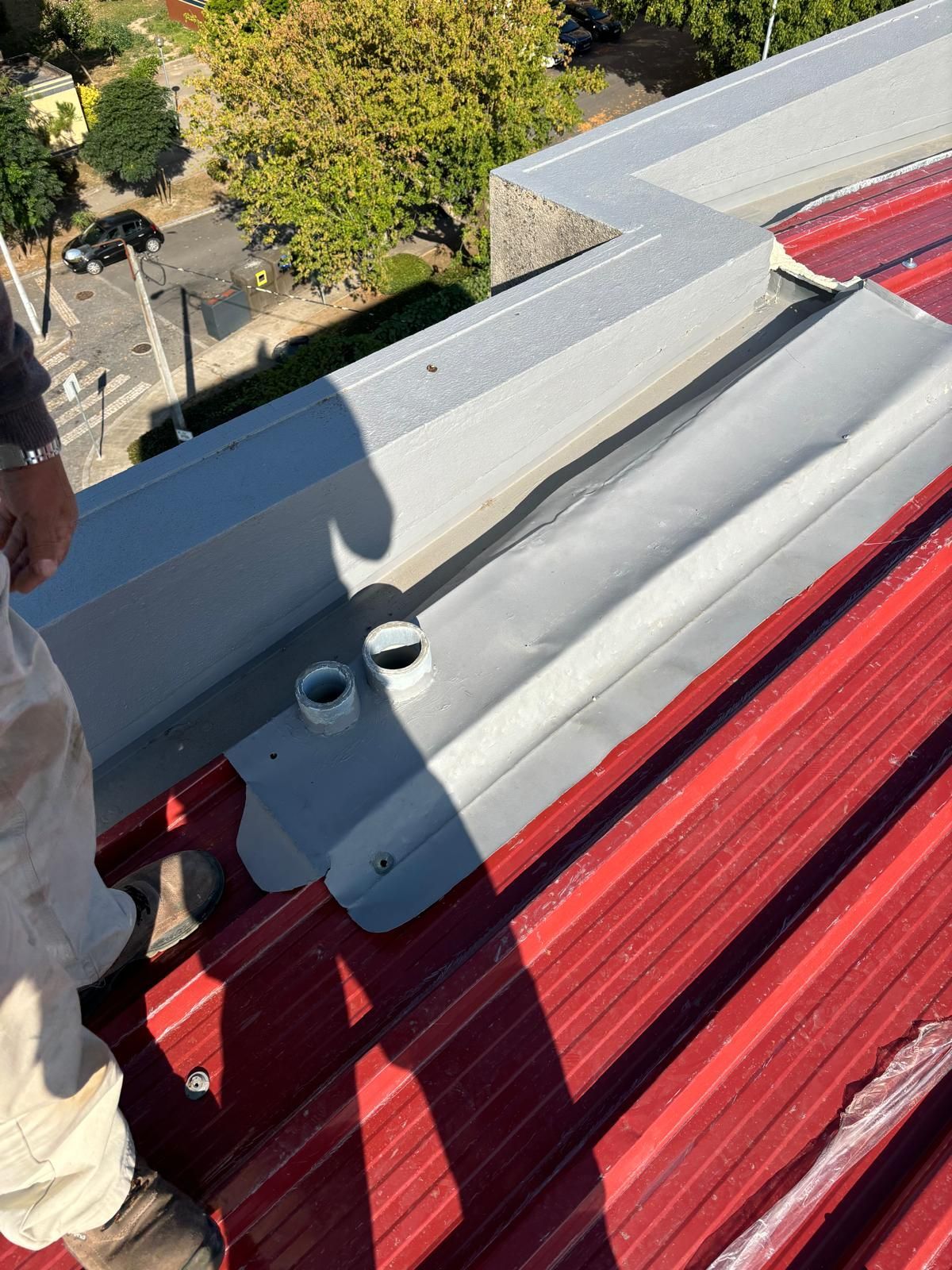 Um homem está em pé no topo de um telhado vermelho.