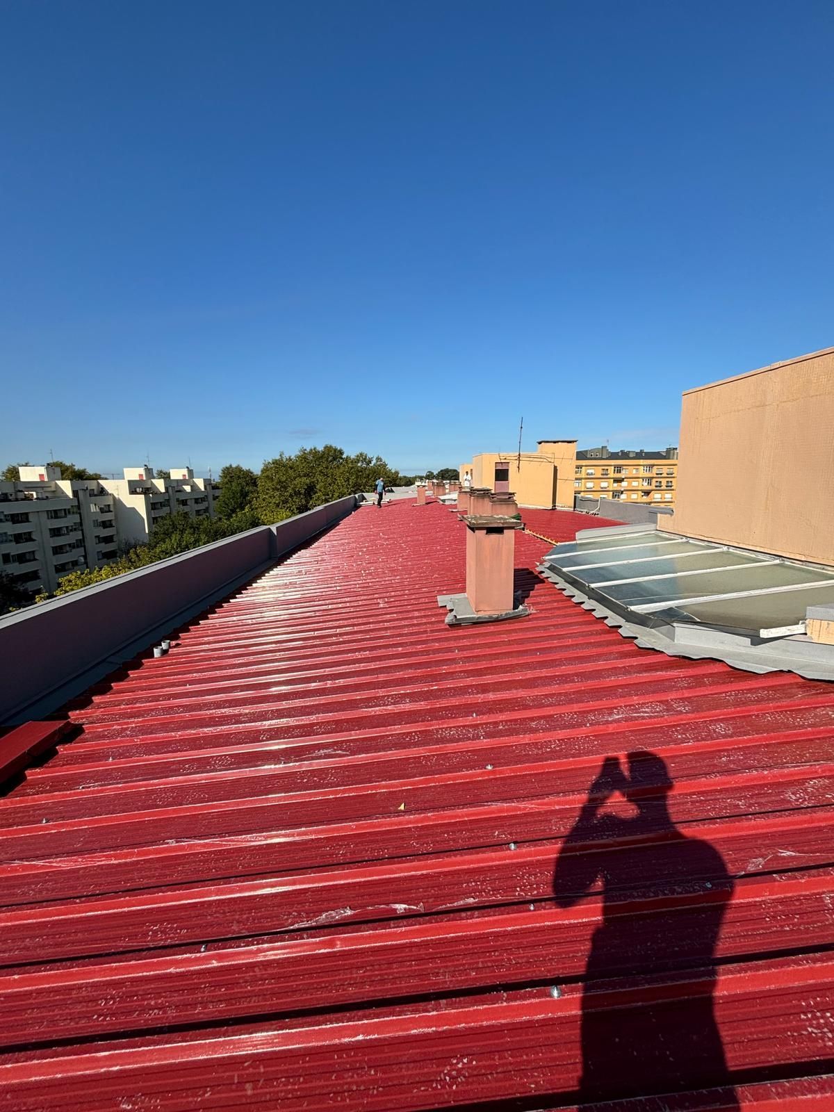Uma pessoa está tirando uma foto de um telhado em painel sandwich 5 ondas 30mm RAL3009 vermelho