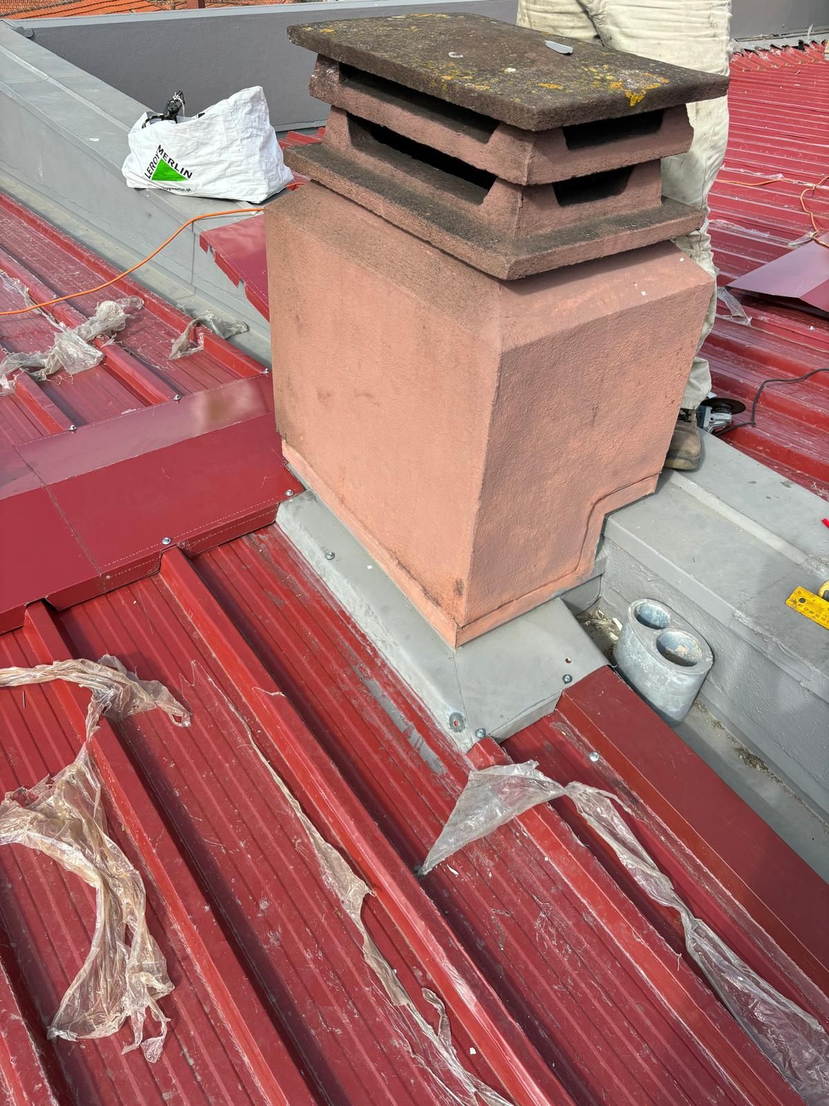 Um telhado em painel sandwich 5 ondas 30mm RAL3009 vermelho com uma chaminé em cima