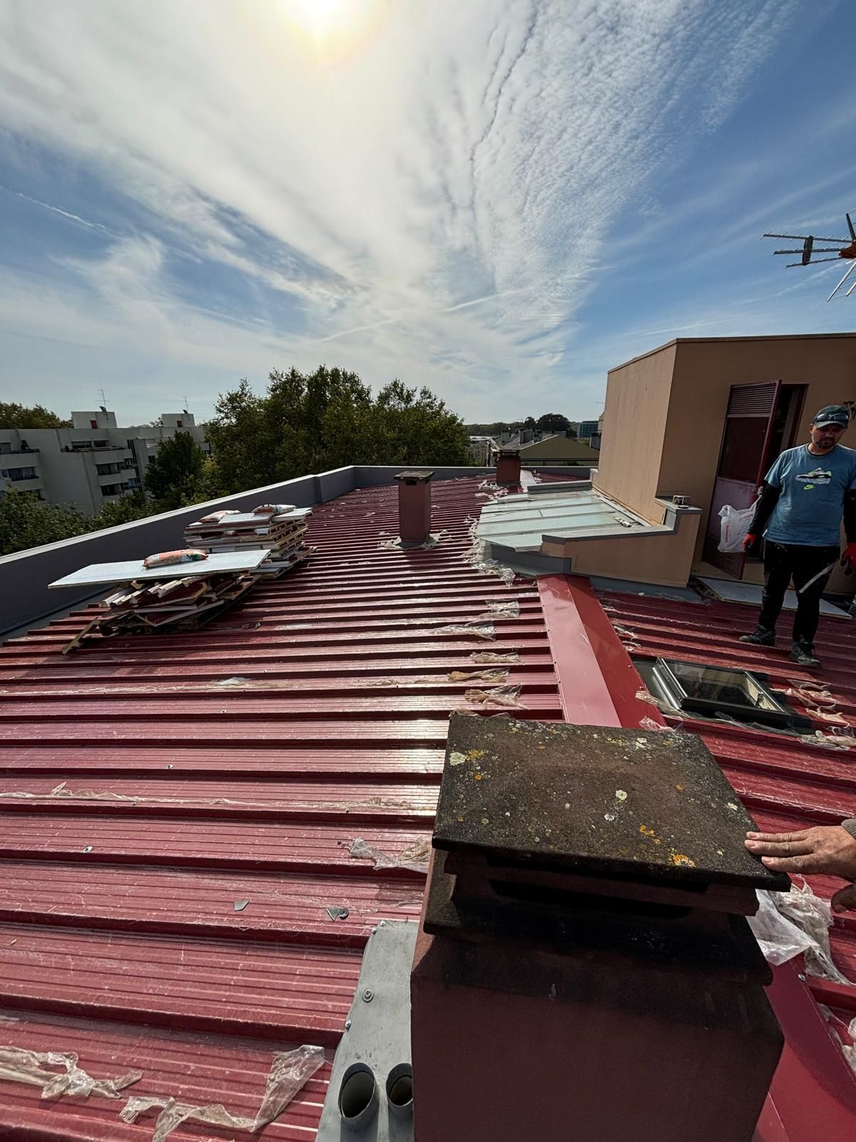 Um homem está em pé no topo de um telhado em painel sandwich 5 ondas 30mm RAL3009 vermelho