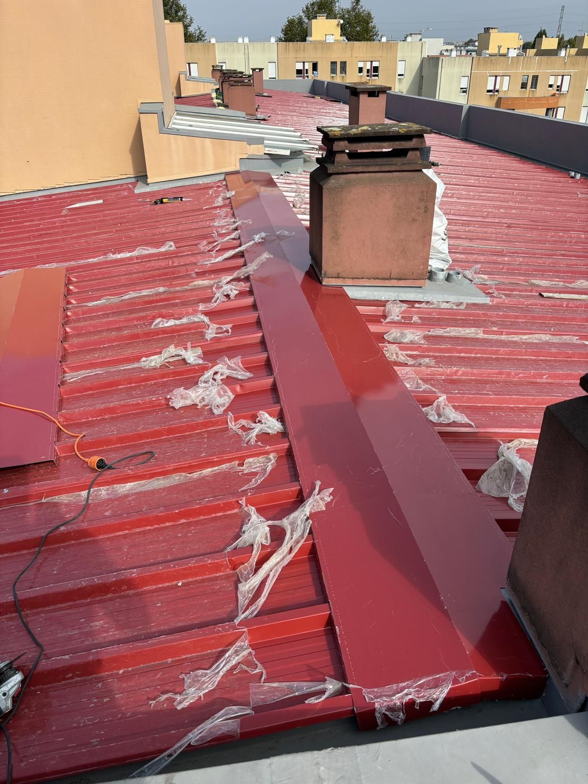 Um telhado em painel sandwich 5 ondas 30mm RAL3009 vermelho com uma chaminé em cima