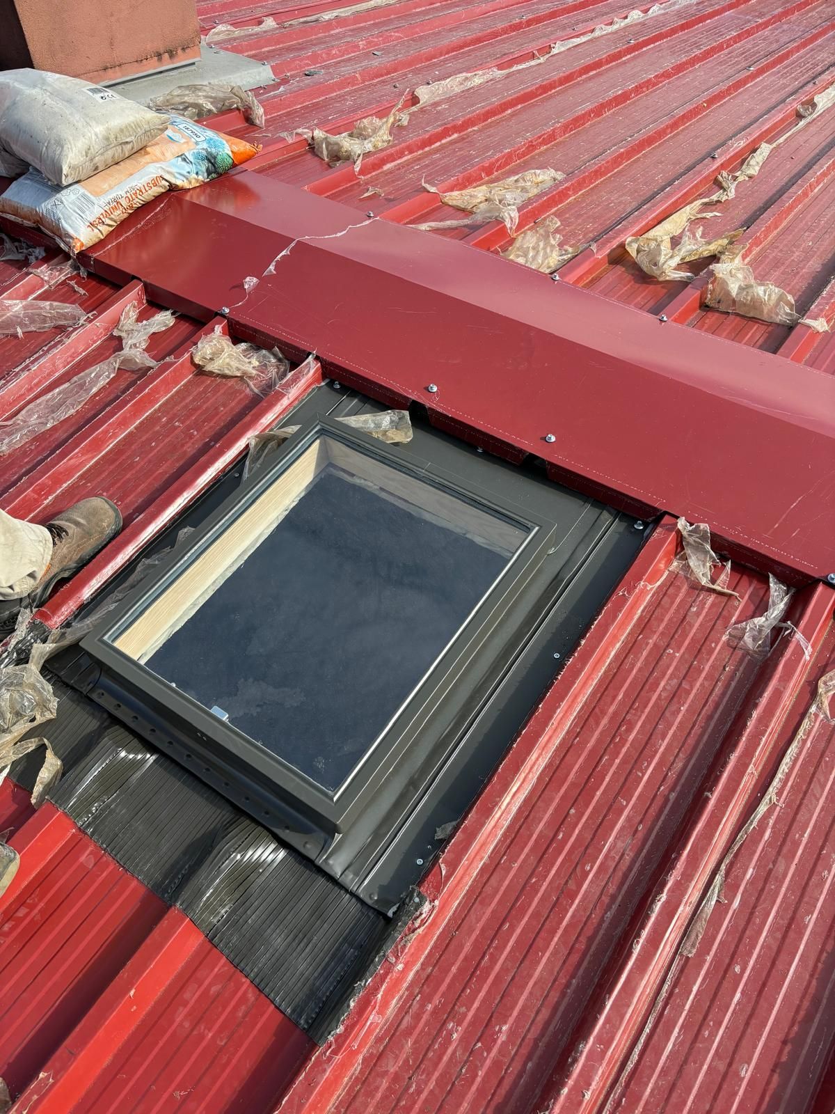 Um telhado vermelho com uma claraboia em cima Velux.