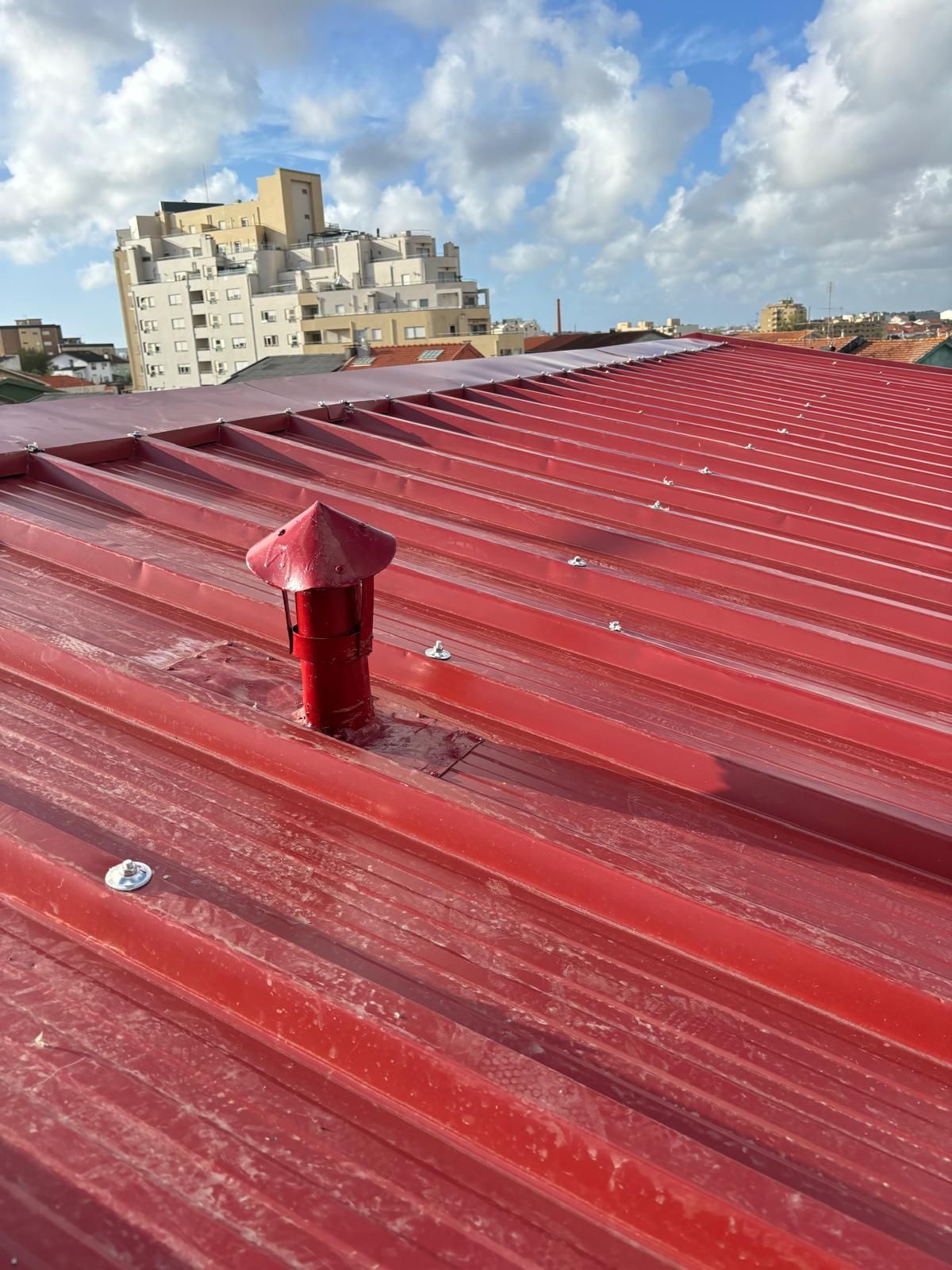 Um telhado em painel sandwich 5 ondas 30mm RAL3009 vermelho com uma chaminé vermelha em cima.