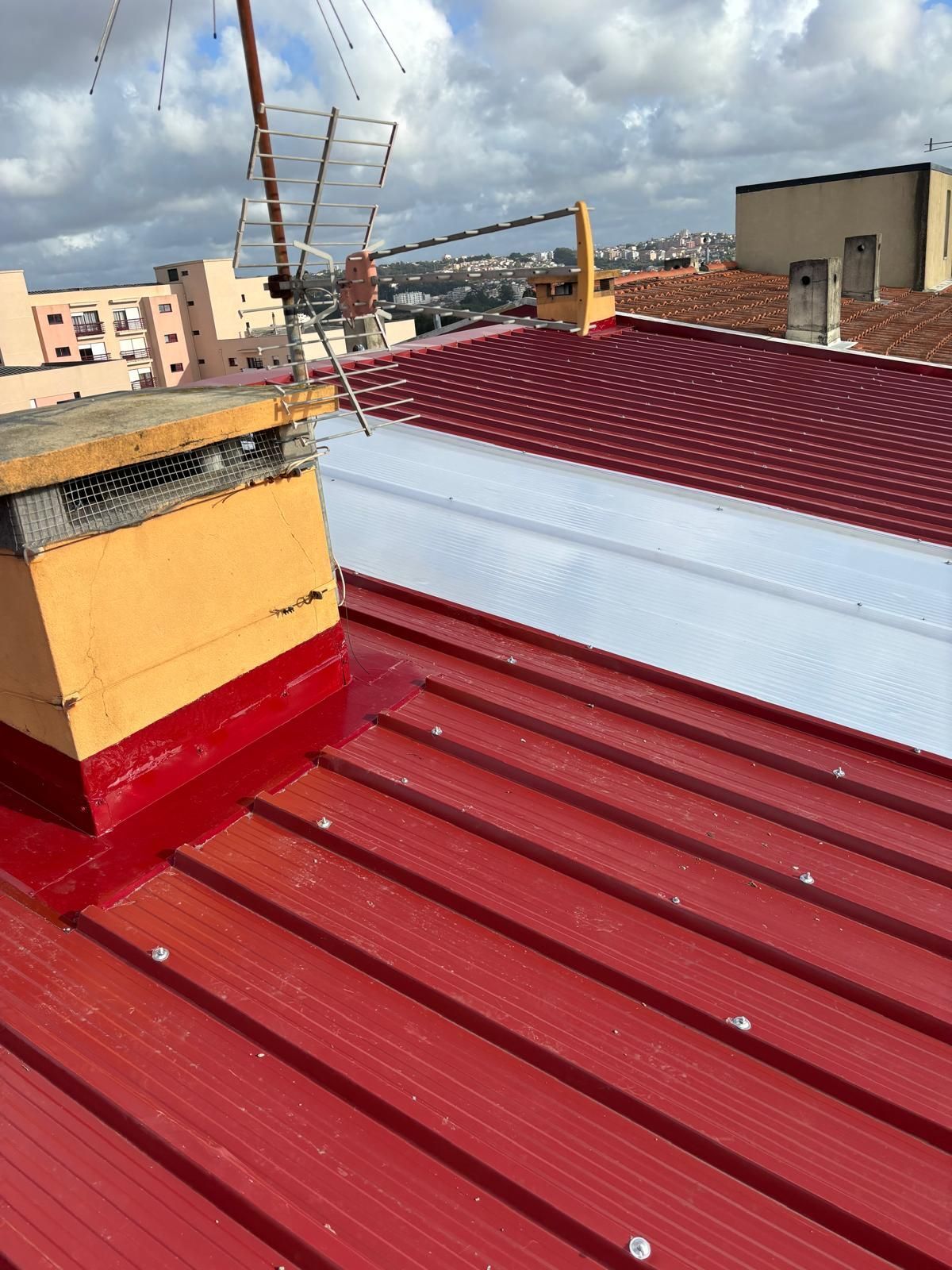 Um telhado em painel sandwich 5 ondas 30mm RAL3009 vermelho com uma chaminé amarela em cima.