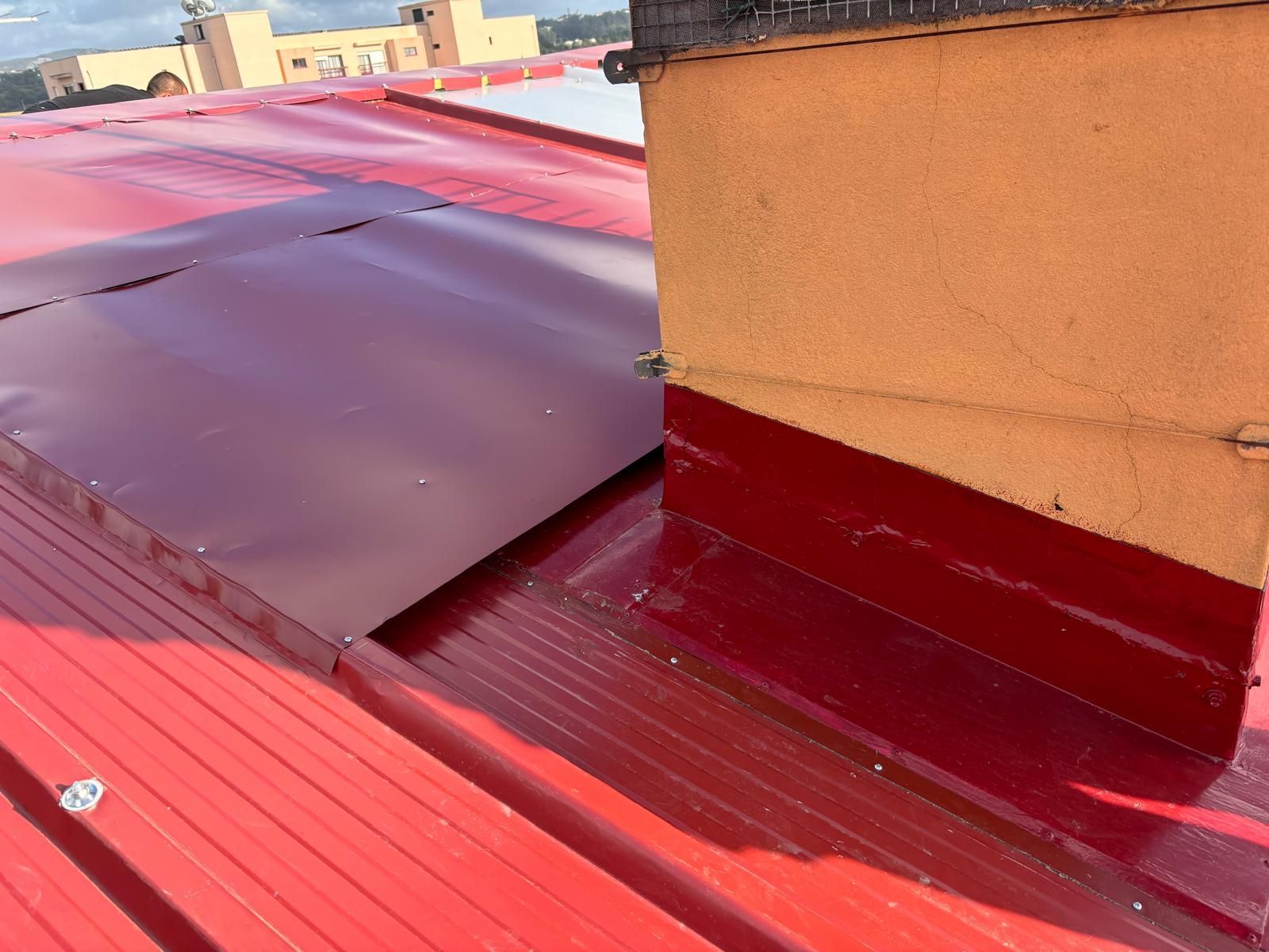 Um telhado vermelho com uma chaminé e um rufo superior à cor