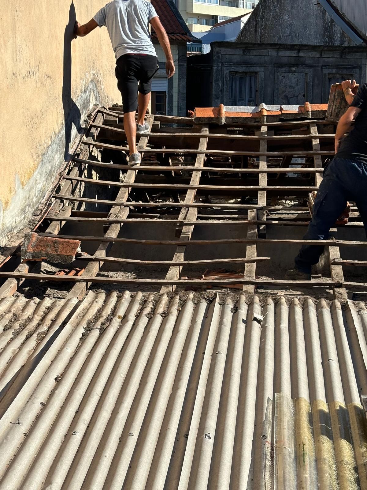 Dois homens estão trabalhando em um telhado de madeira e metal ondulado