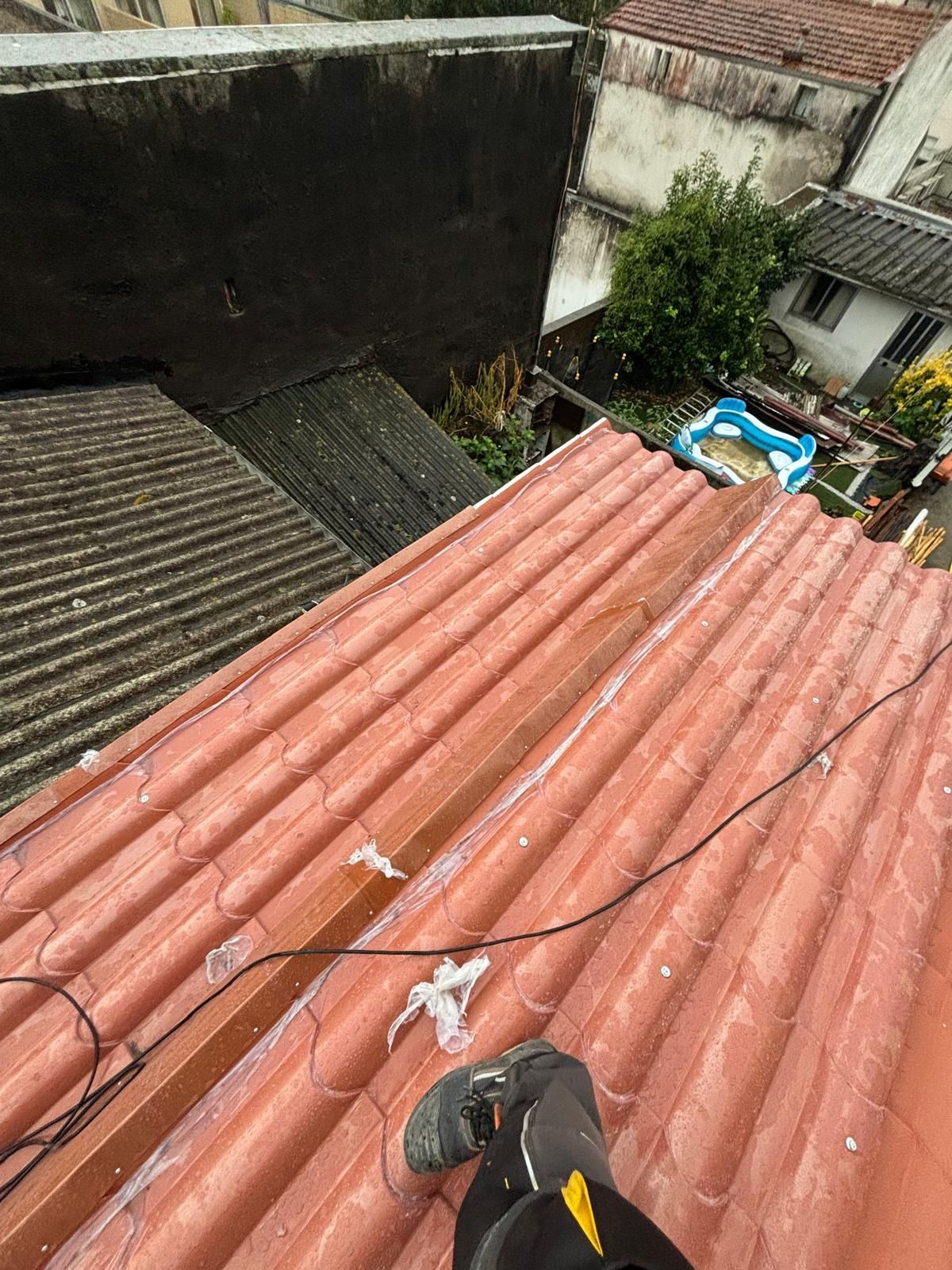 Uma pessoa está de pé no topo de um telhado de telhas vermelhas.