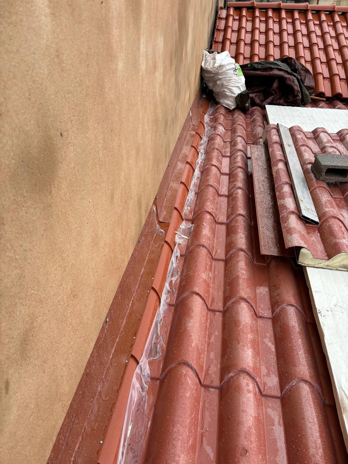 Um telhado de telhas vermelhas com um ralo na lateral de um prédio.