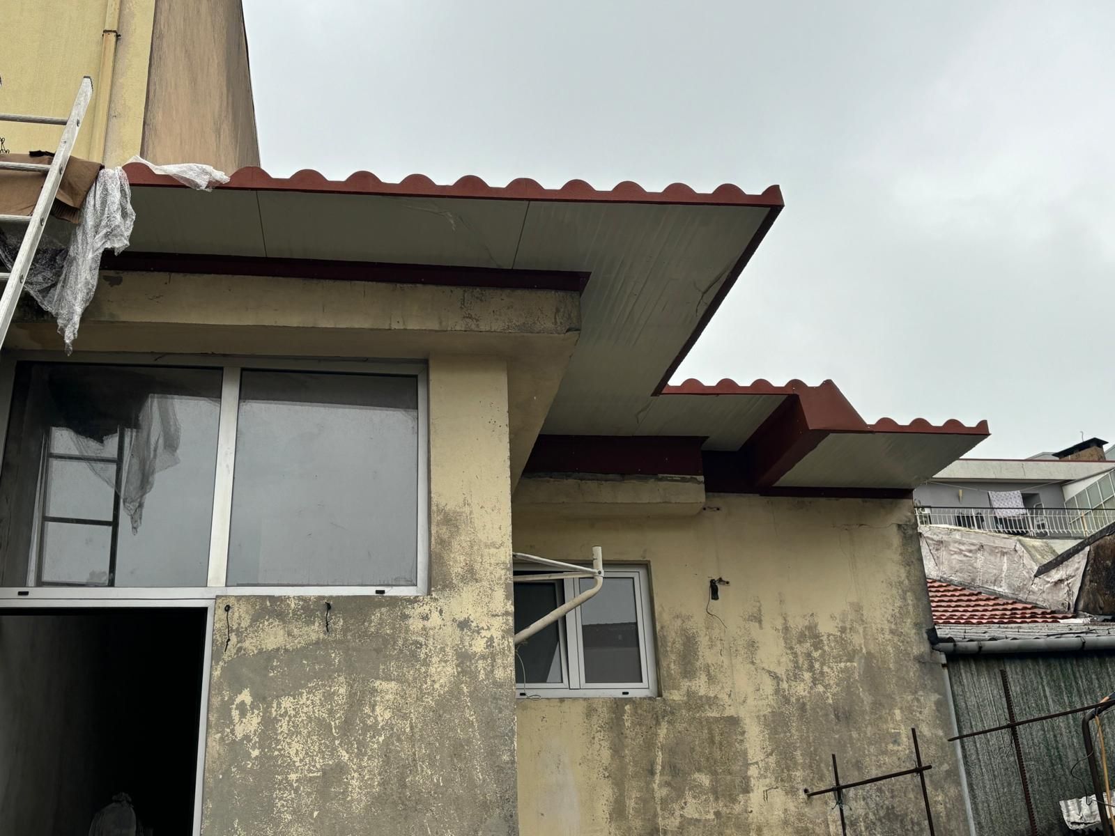 Um prédio com um telhado vermelho e uma janela.