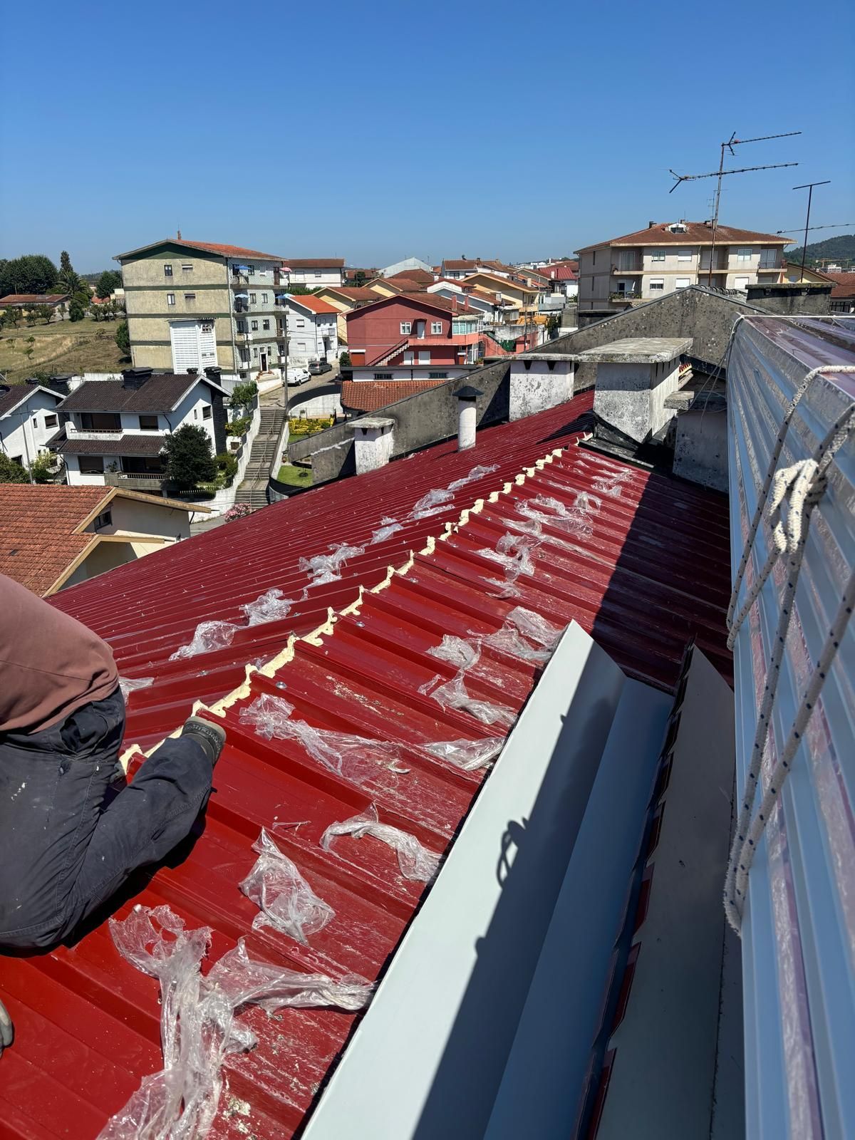 Um homem está trabalhando no telhado de um prédio em painel sandwich 5 ondas 30mm