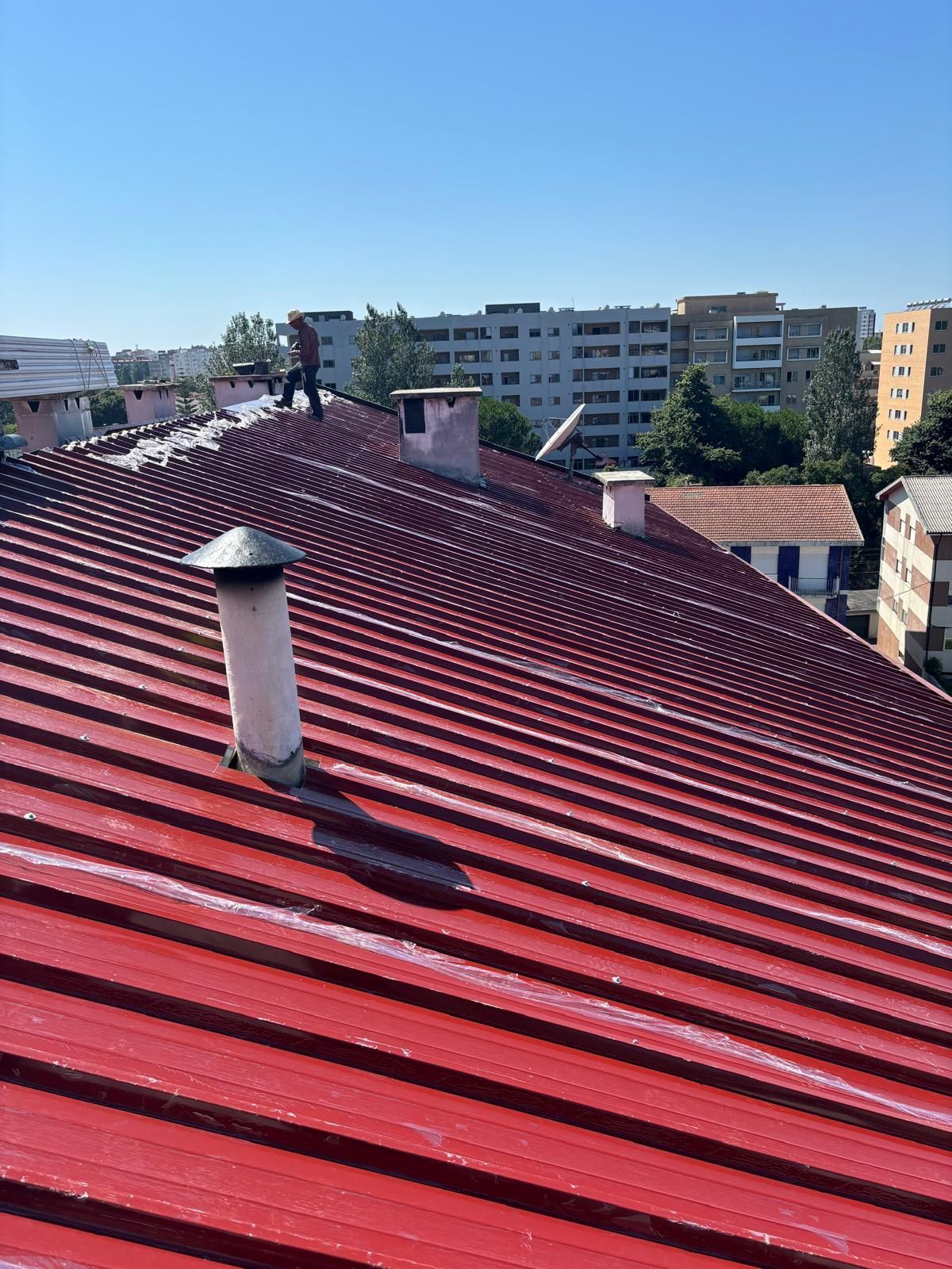 Um homem está em pé no topo de um telhado em painel sandwich 5 ondas 30mm vermelho.