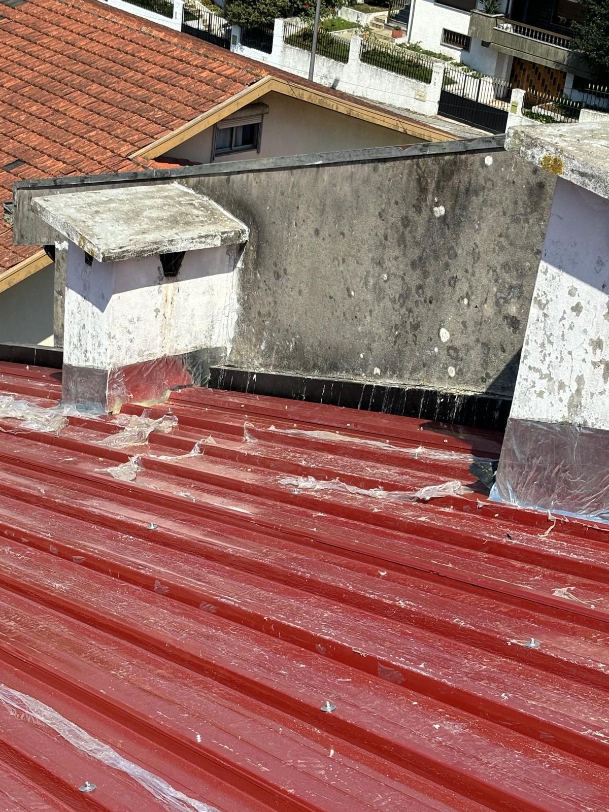 Um telhado em painel sandwich 5 ondas 30mmvermelho com uma chaminé em cima.