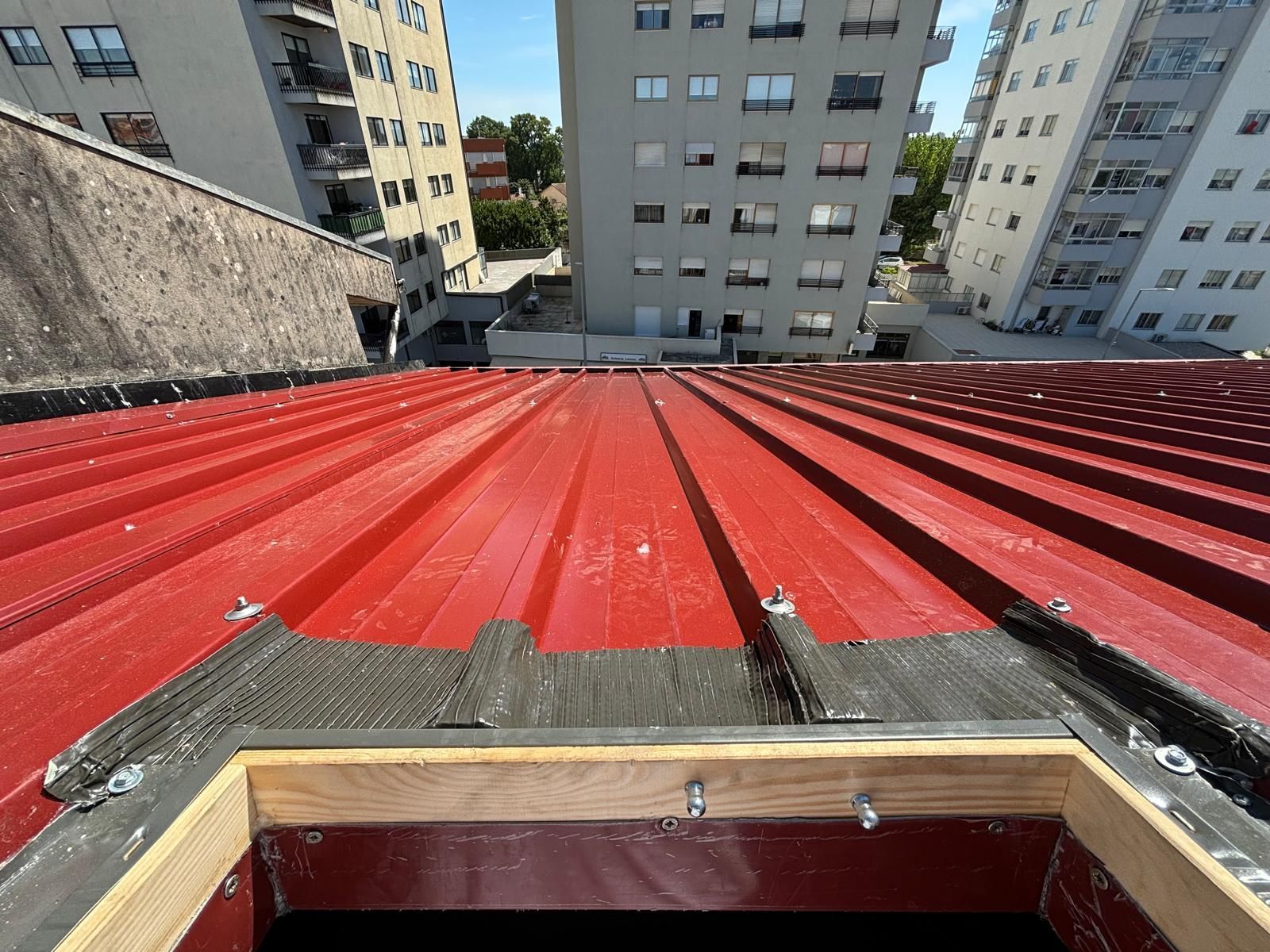 Olhando para um telhado vermelho com prédios ao fundo