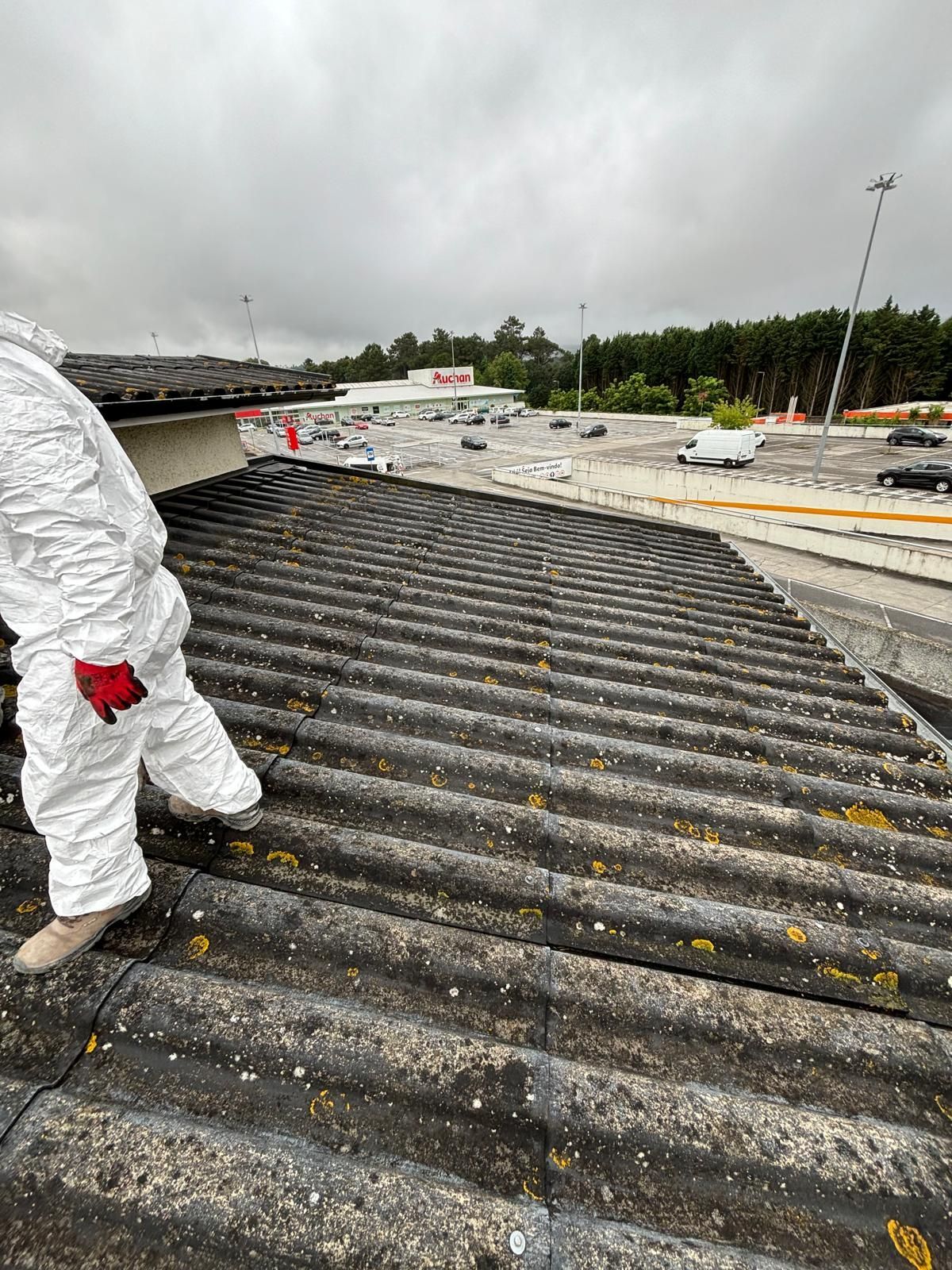 Um homem em um traje de proteção fato tyvek branco proteção de amianto está em pé no topo de um telhado.