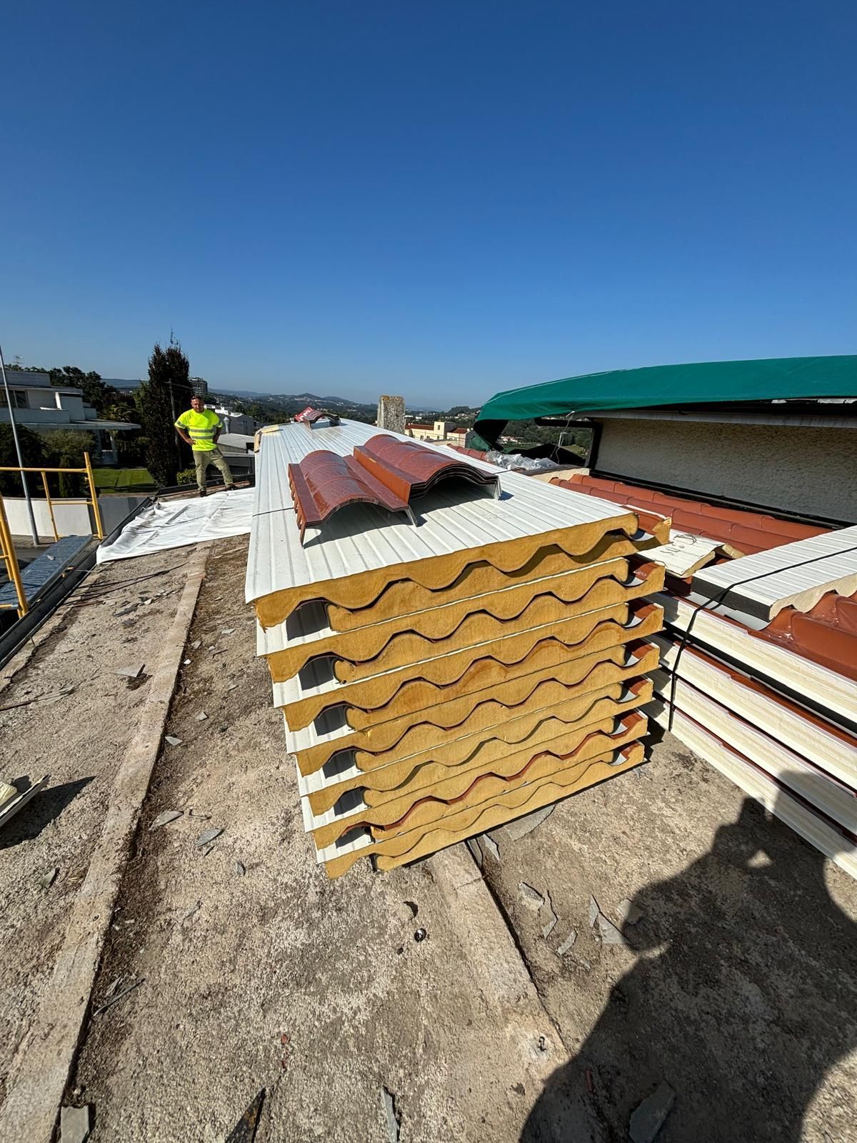 Uma pilha de painéis de telhado sobre um telhado em placa de betão.