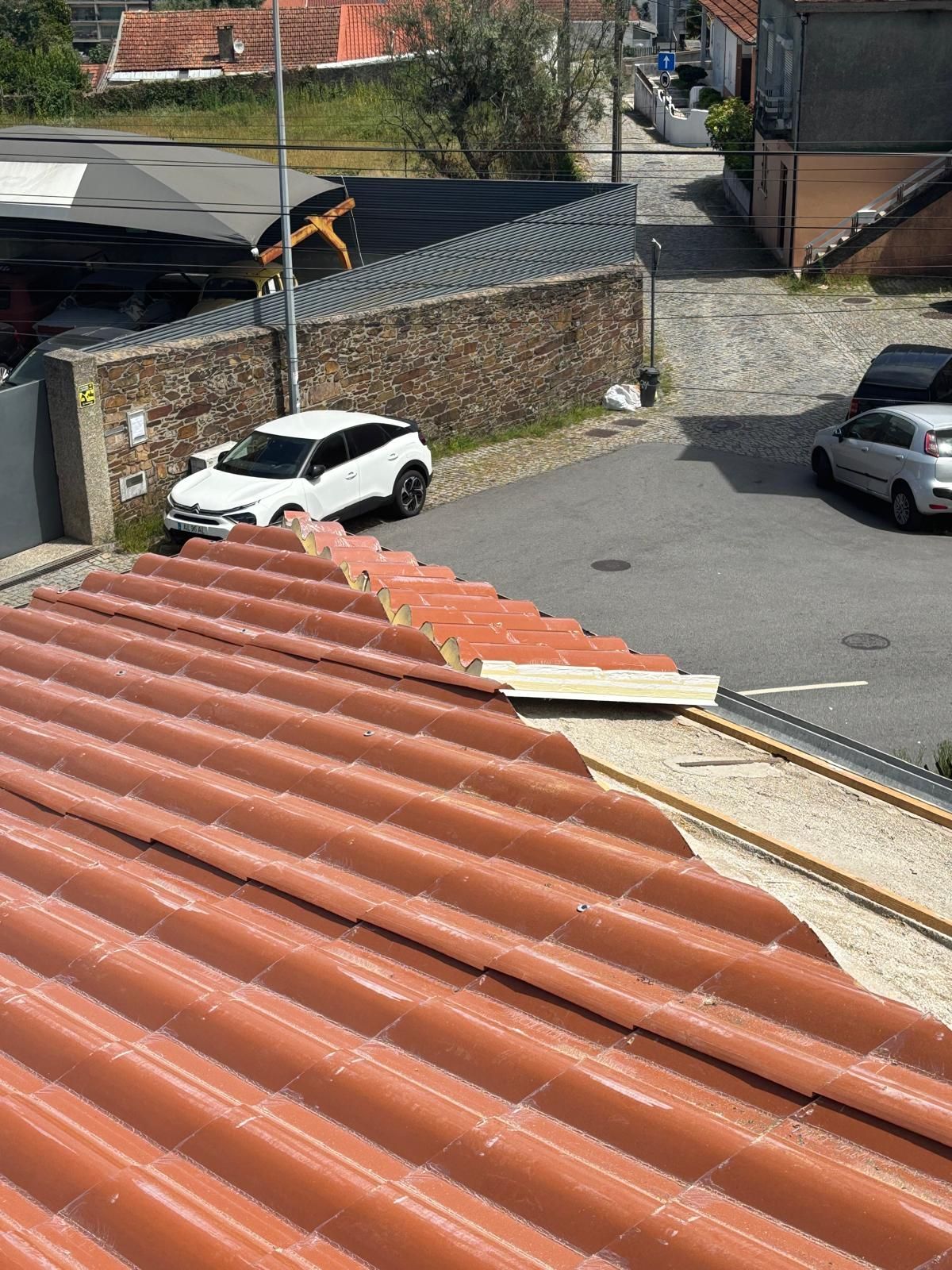 Um carro branco está estacionado na beira da estrada próximo a um telhado.