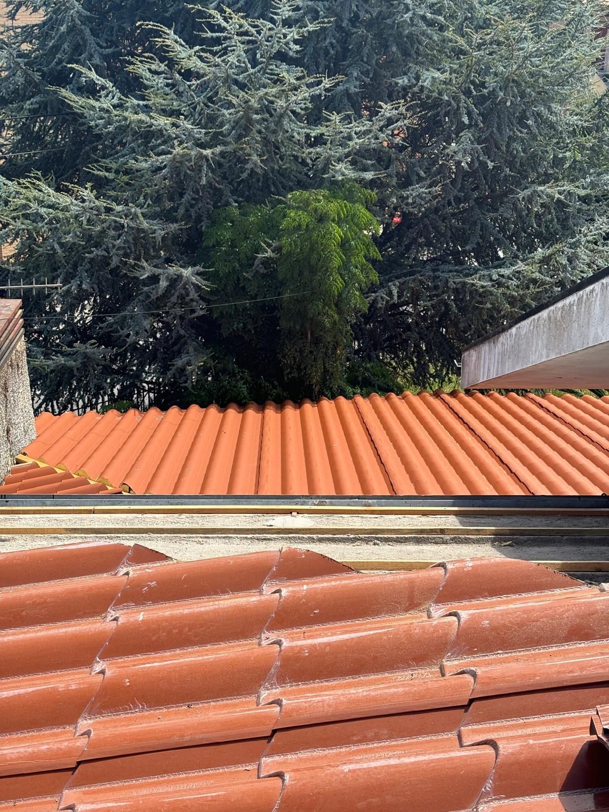 Um telhado de telhas painel sandwich imitação de telha lusa 45mm laranja RAL8004 com árvores ao fundo