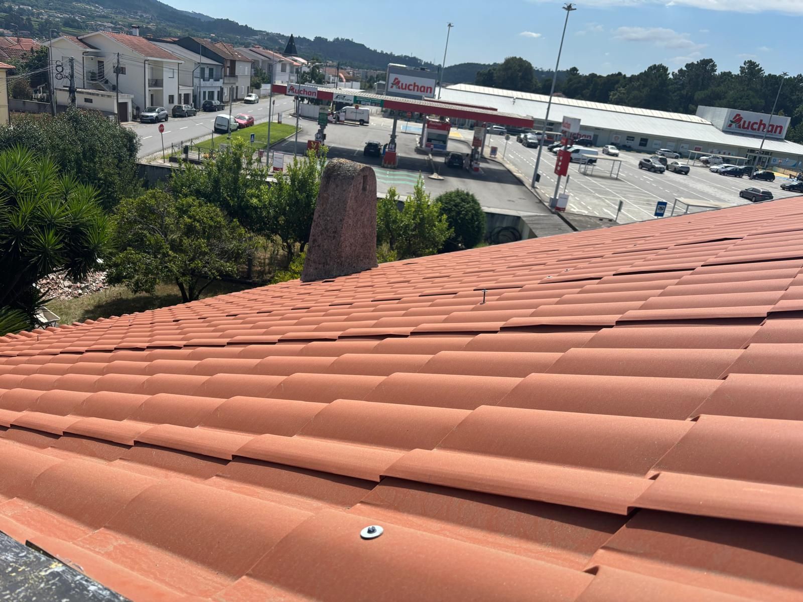 Um telhado de telhas vermelhas com um posto de gasolina ao fundo