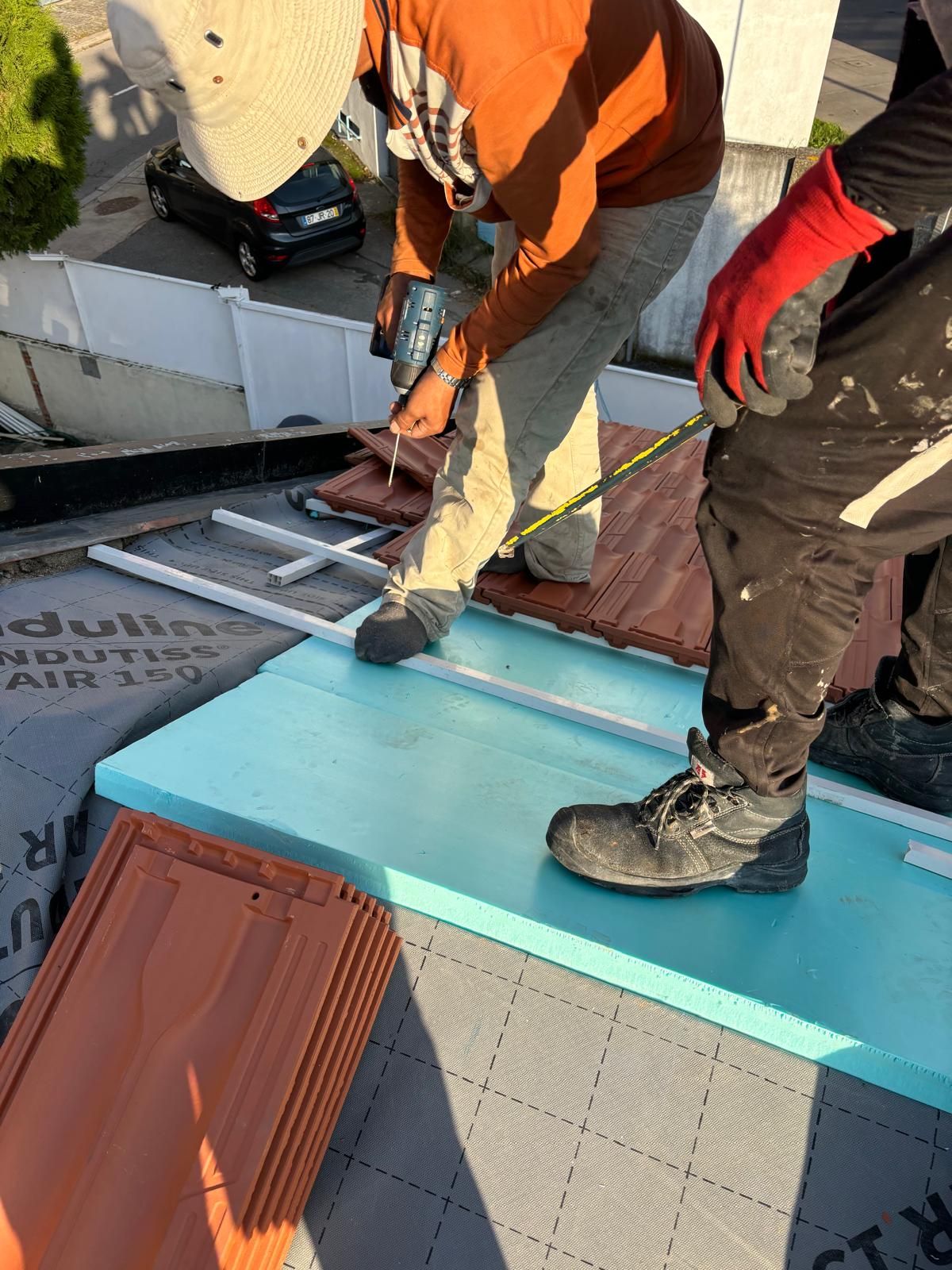 Um homem está medindo um pedaço de espuma em um telhado.