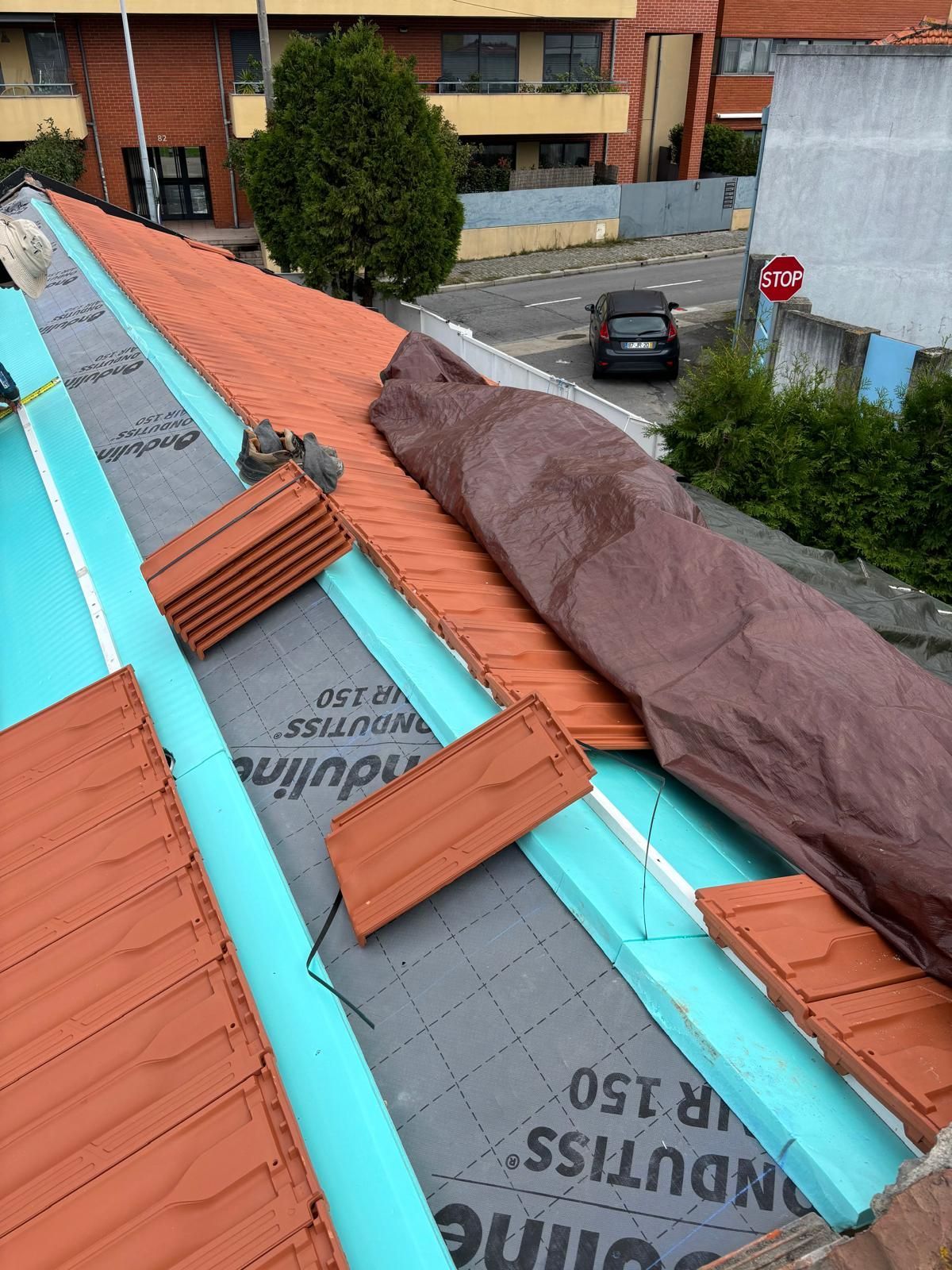 Um telhado com uma calha azul e telhas cerâmicas laranjas