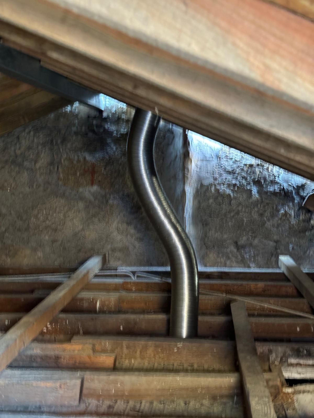 Um cano de metal está passando por uma estrutura de madeira.