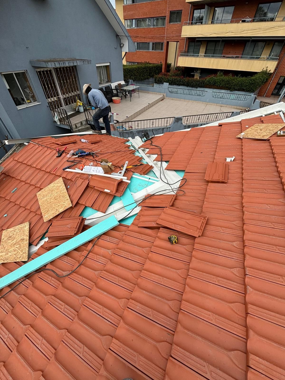 Um homem está trabalhando no telhado de uma moradia.