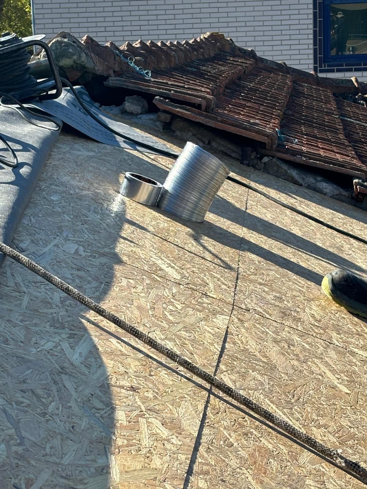 Um close de um telhado com muitas ferramentas nele, forrado com madeira OSB 15mm ou 12mm