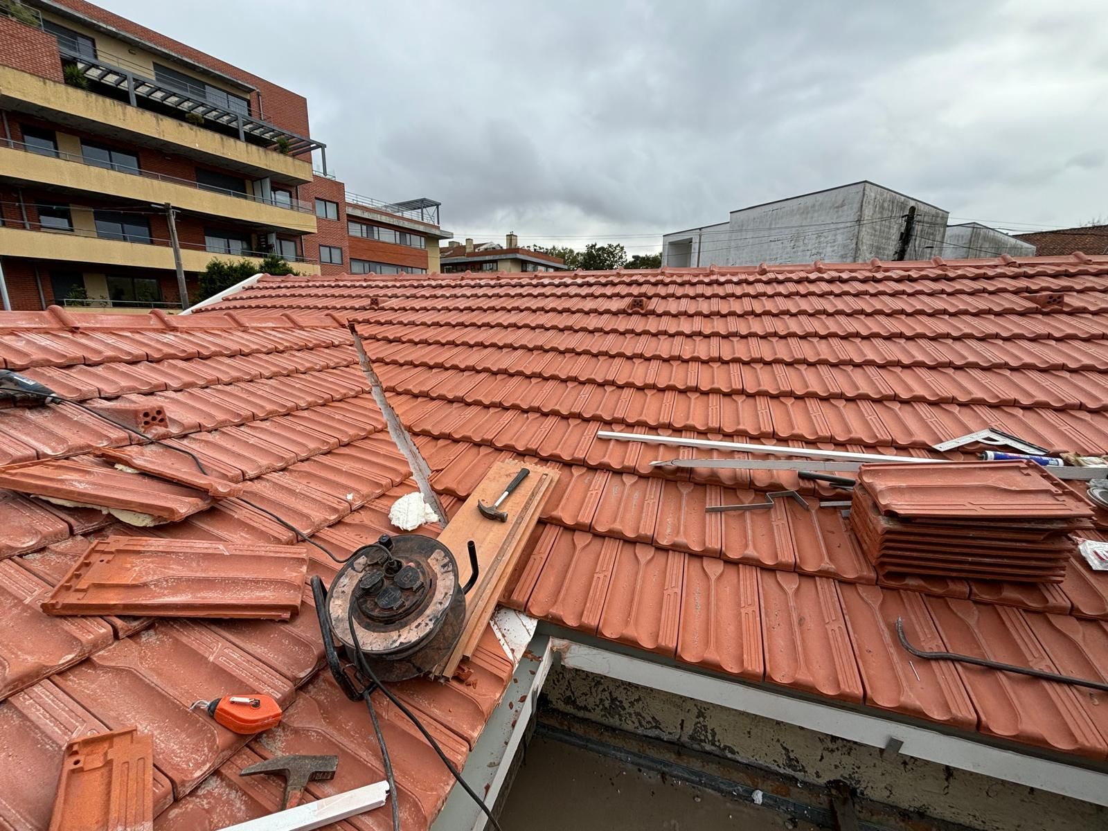 Um telhado com muitas telhas cerâmicas laranjas e ferramentas.