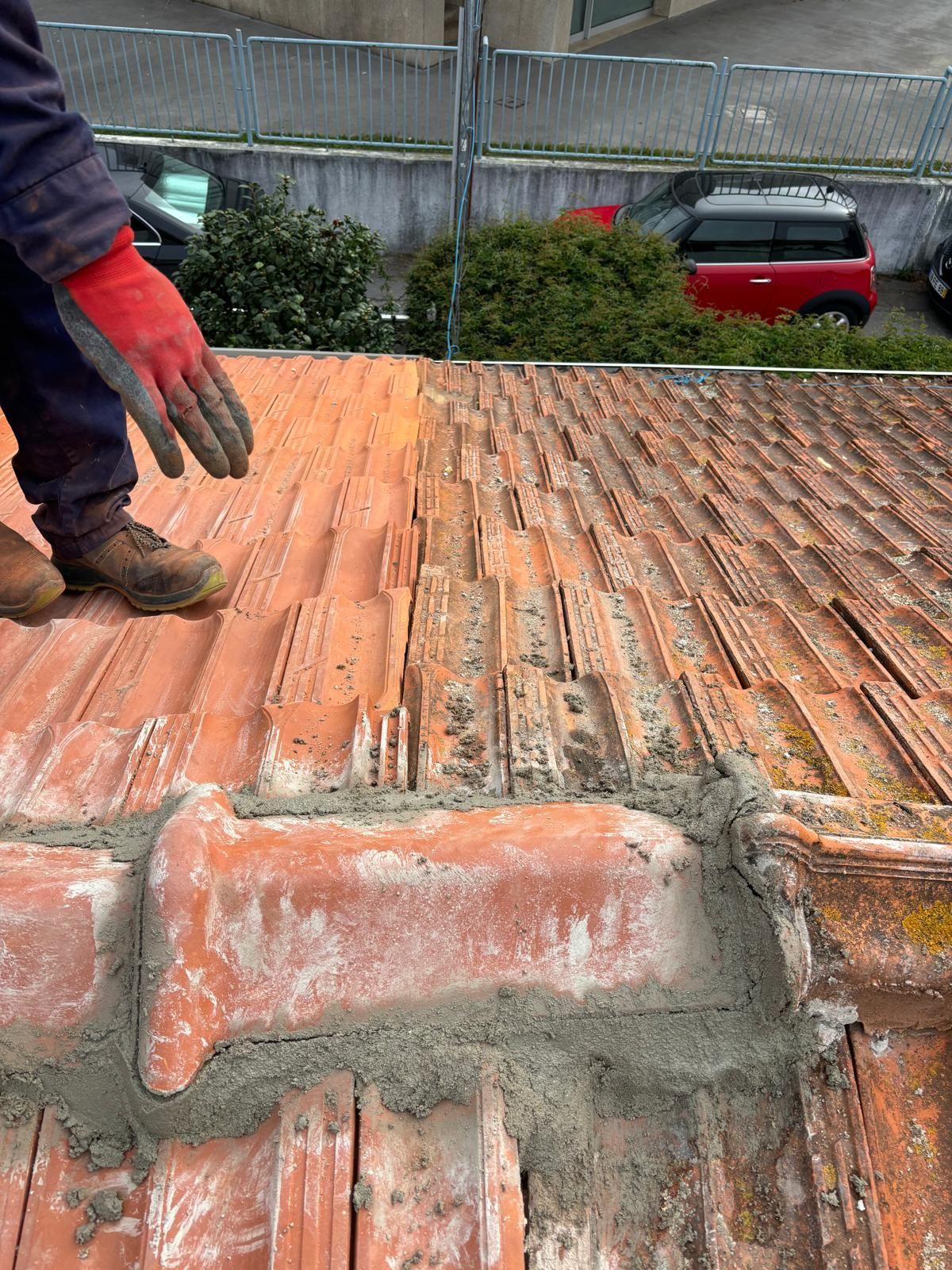 Um homem usando luvas vermelhas está em pé no topo de um telhado de telhas.