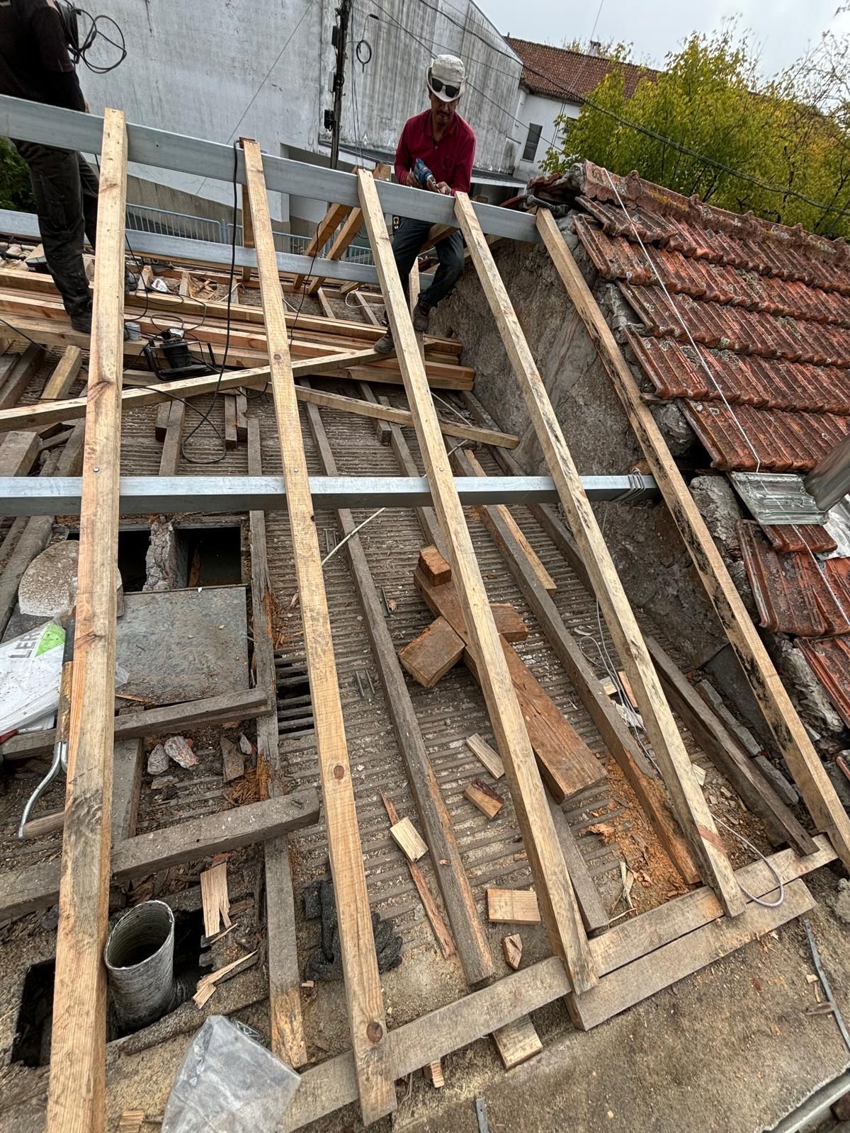 Um homem está trabalhando no telhado de um prédio com vigas de madeira e Viga principal em tubo galvanizado 12x10 6 metros.