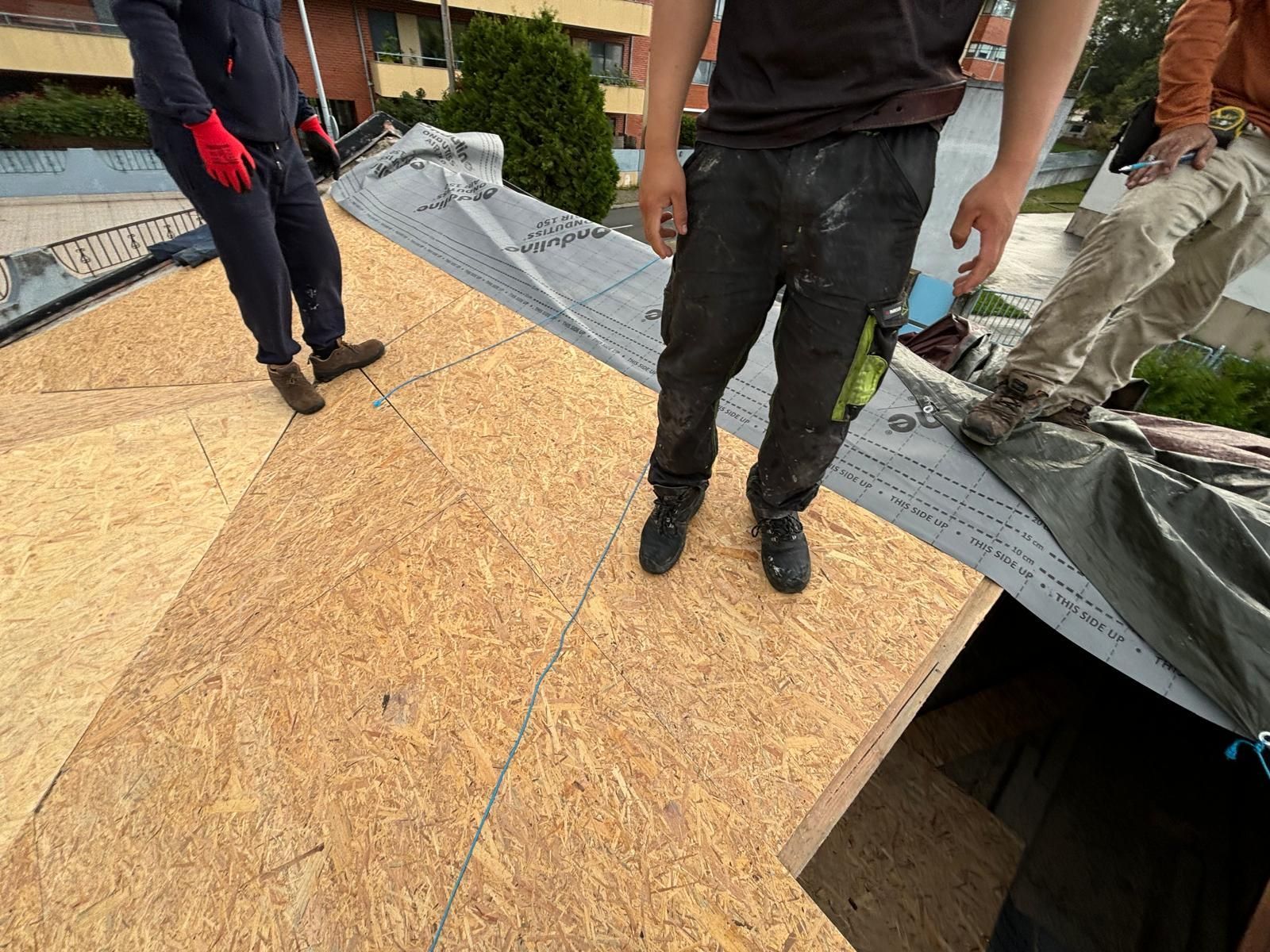 Um grupo de homens está em pé no topo de um telhado de madeira.