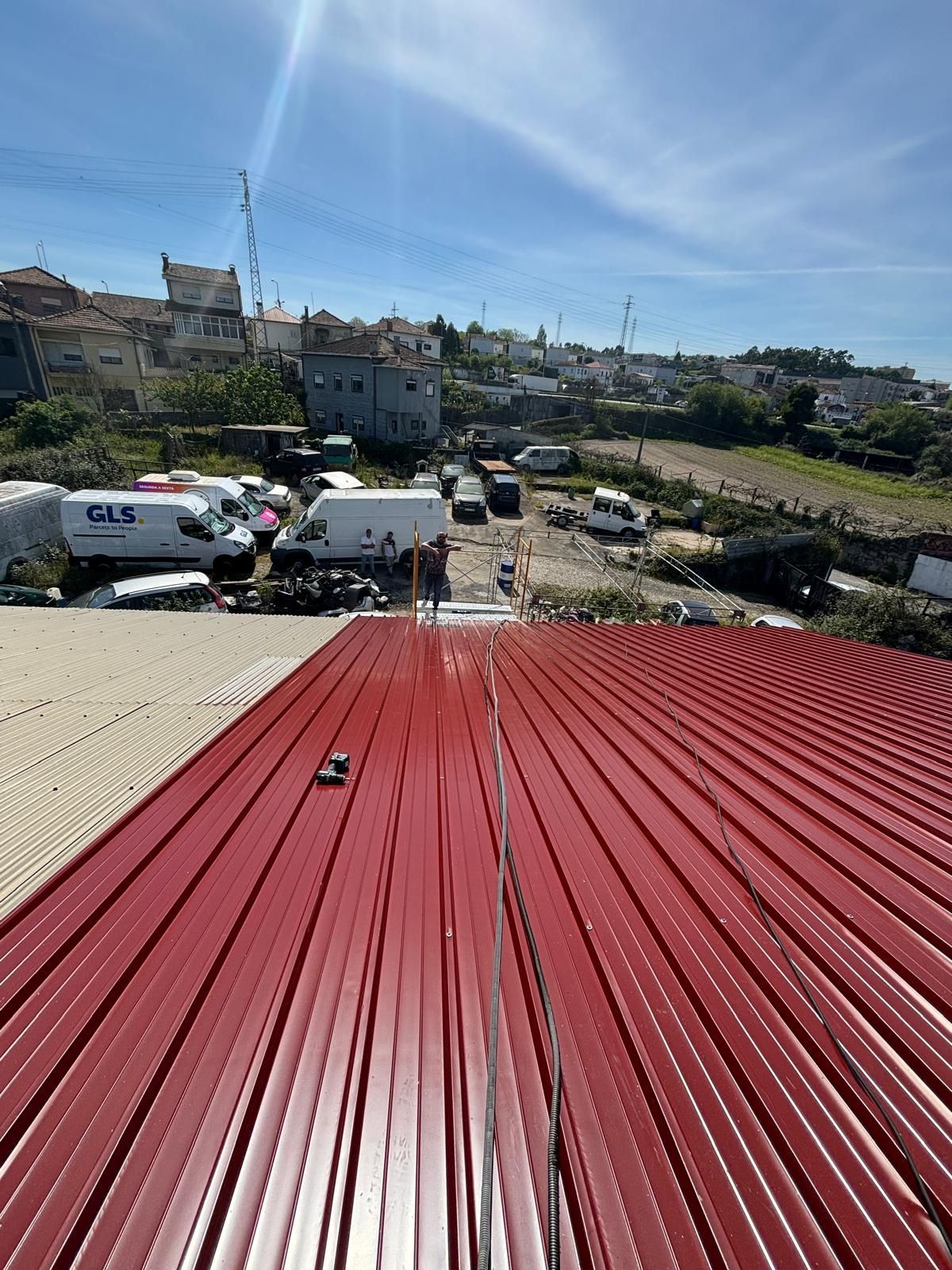 Um telhado em painel sandwich 5 ondas 30mm de um prédio com muitos carros estacionados nele.