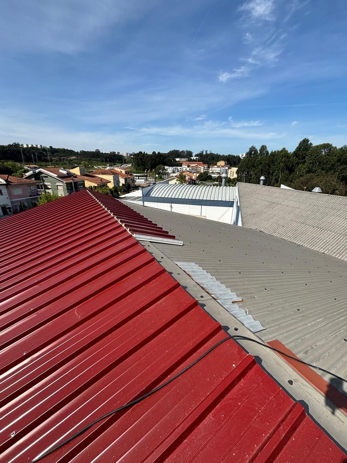 Um telhado vermelho com um telhado cinza ao fundo