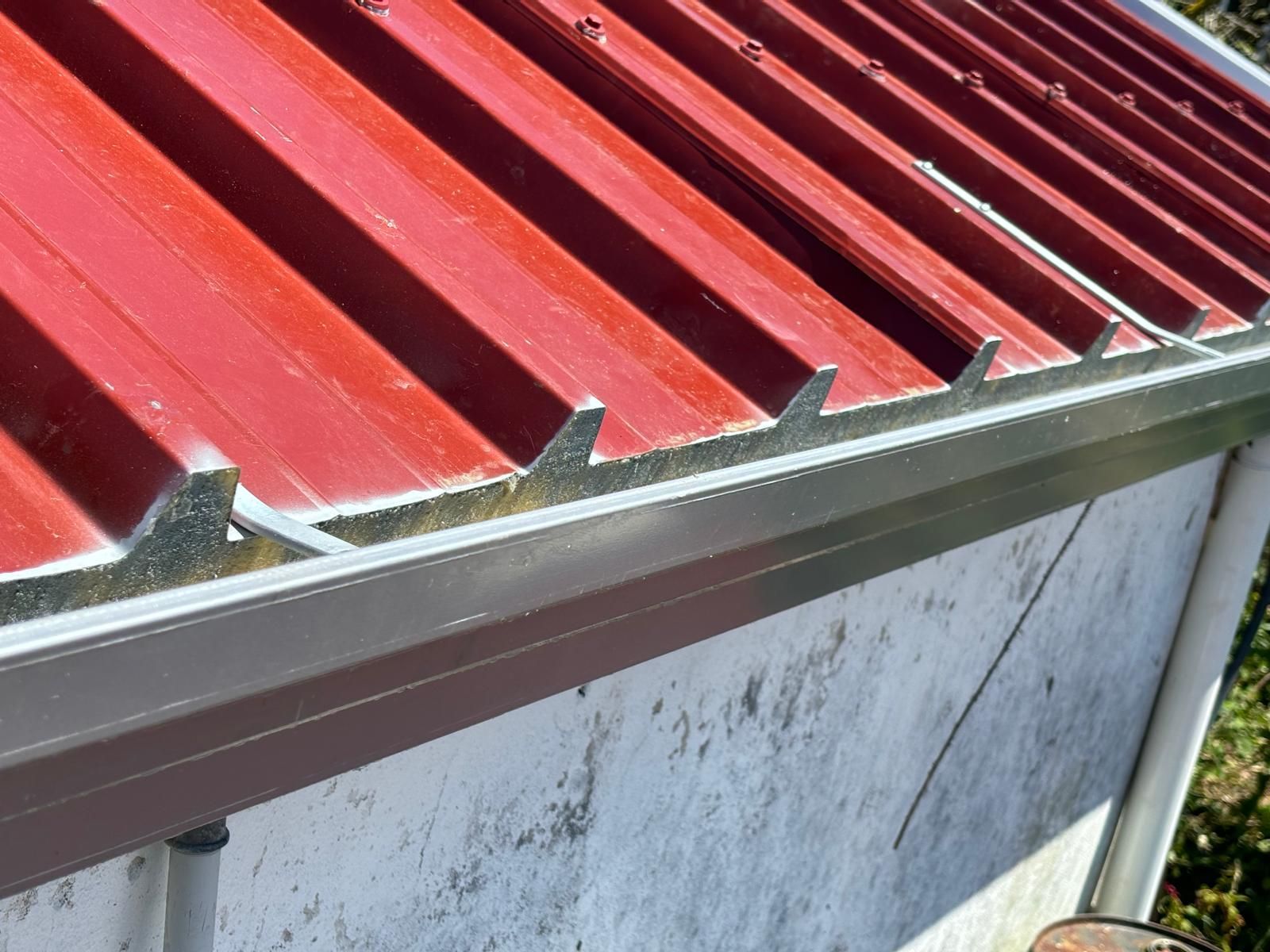 Um telhado vermelho com uma calha de metal