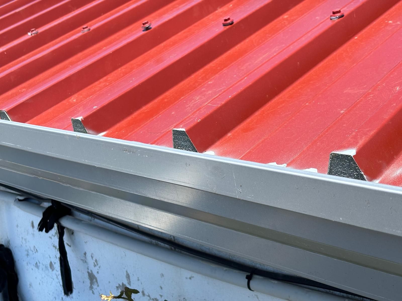 Um telhado em painel sandwich 5 ondas 30mmvermelho com uma calha branca.