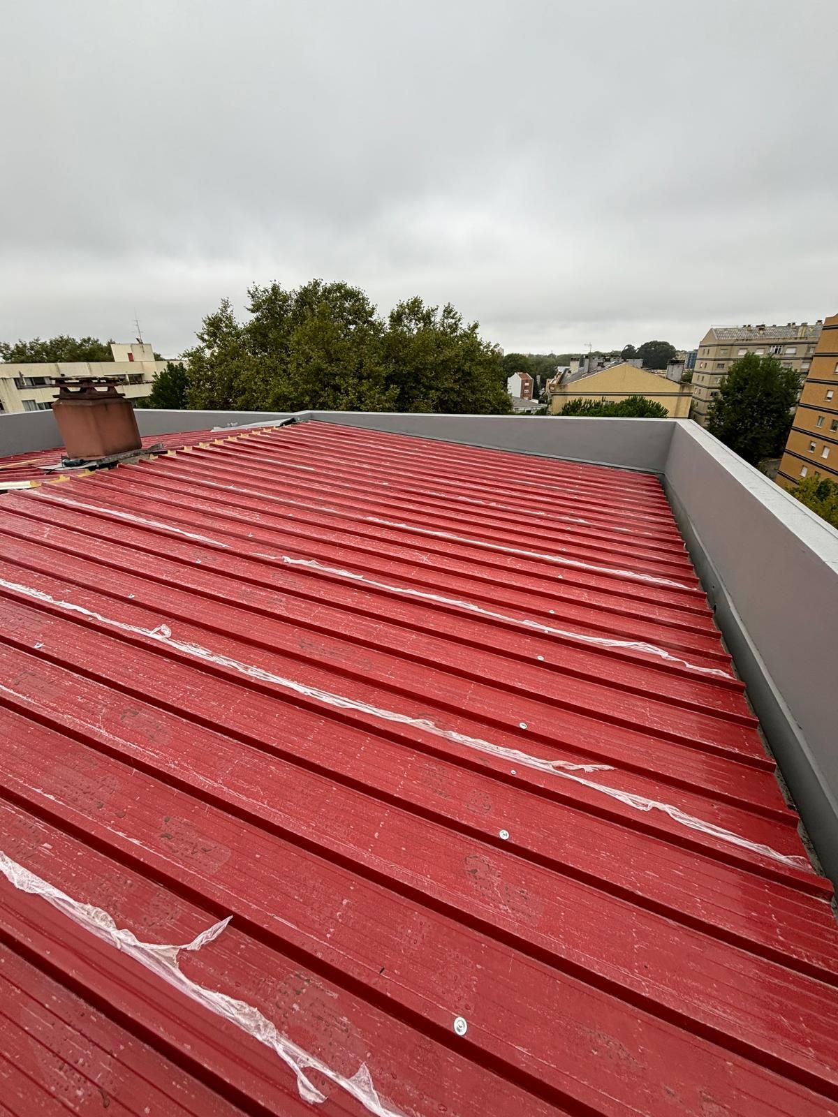 Um telhado de metal telhado em painel sandwich 5 ondas 30mm RAL3009 vermelho com uma chaminé em cima.