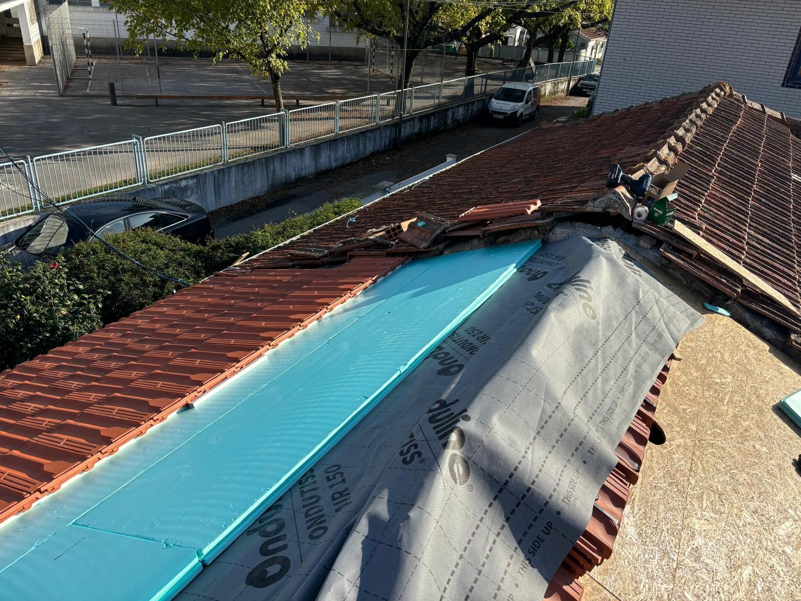 Um telhado com uma lona azul está sendo consertado.