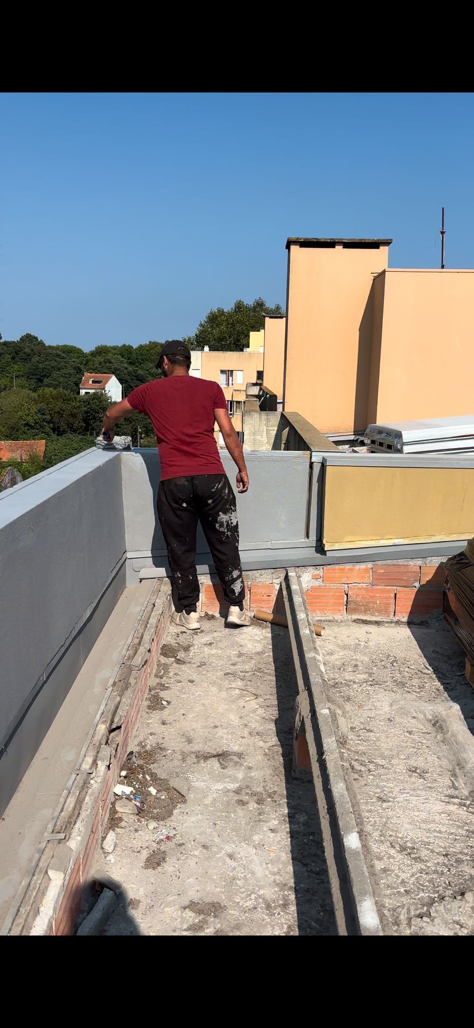 Um homem está caminhando por uma passarela de concreto no topo de um prédio.
