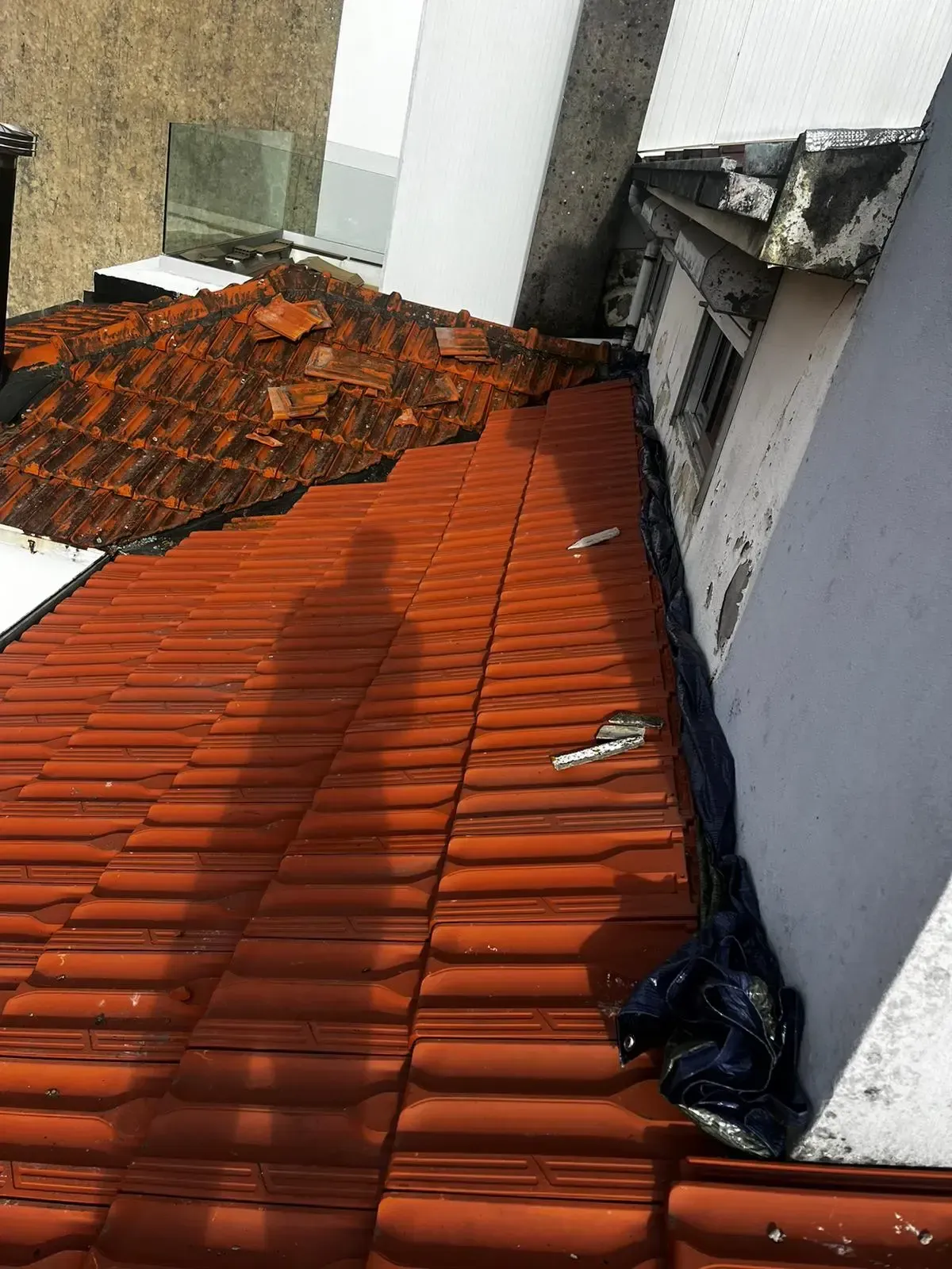 Um telhado com muitas telhas e um prédio ao fundo.