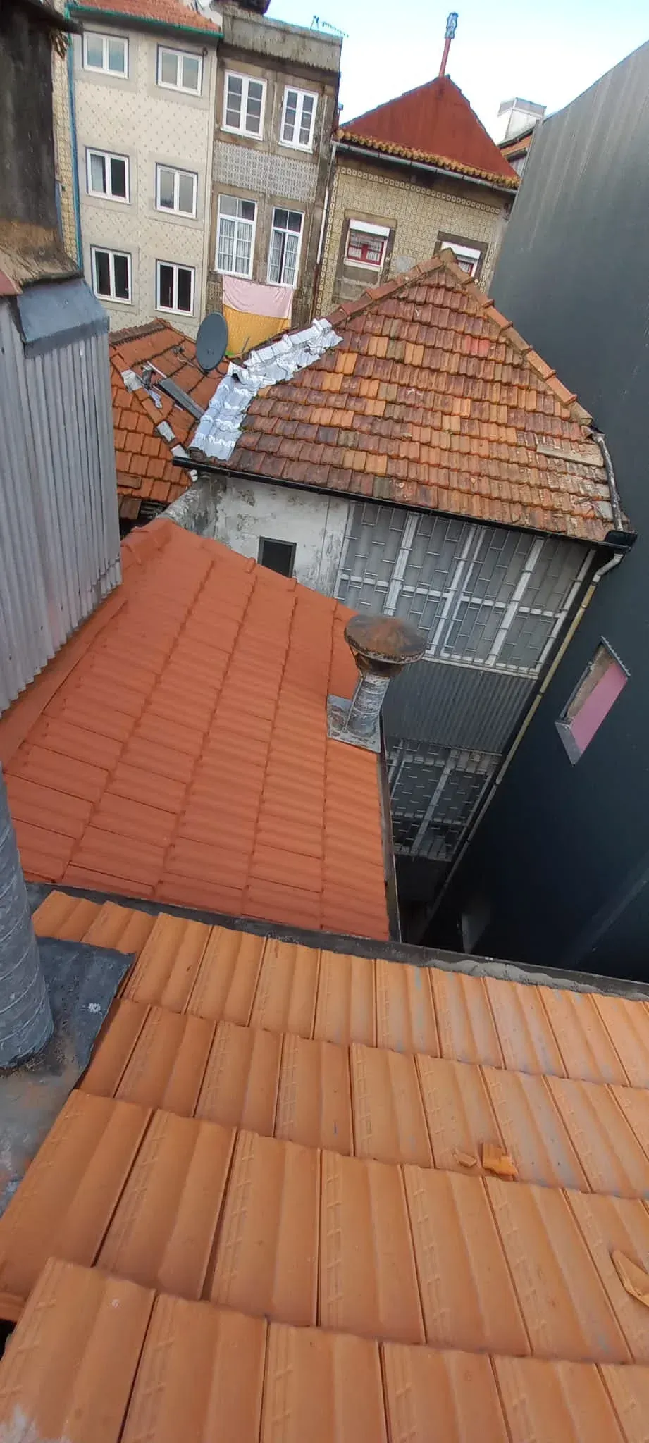 Um telhado com muitas telhas e um prédio ao fundo.