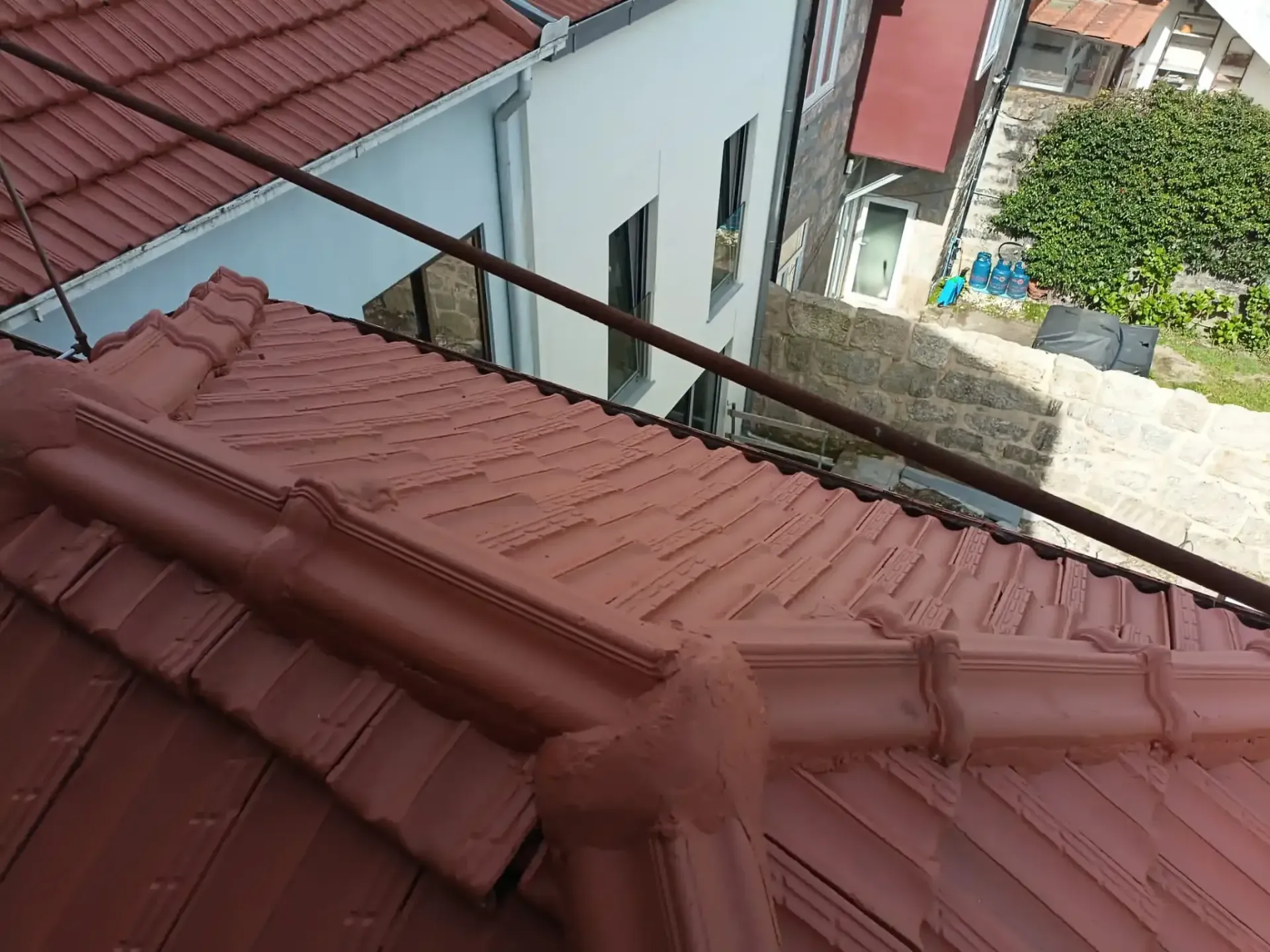 O telhado de um prédio com telhas vermelhas e uma grade de metal.