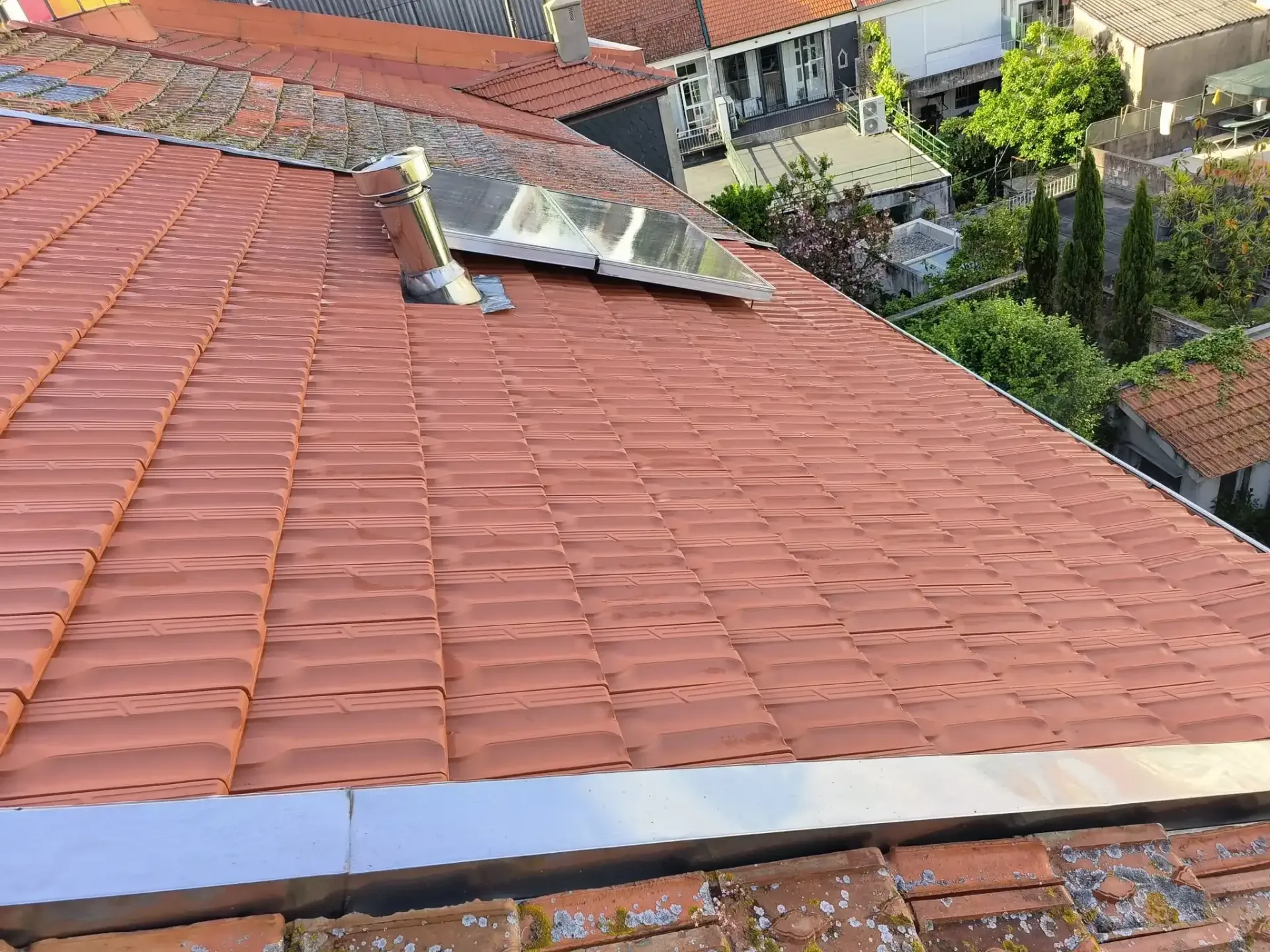 Um telhado de telhas vermelhas com uma claraboia no topo.