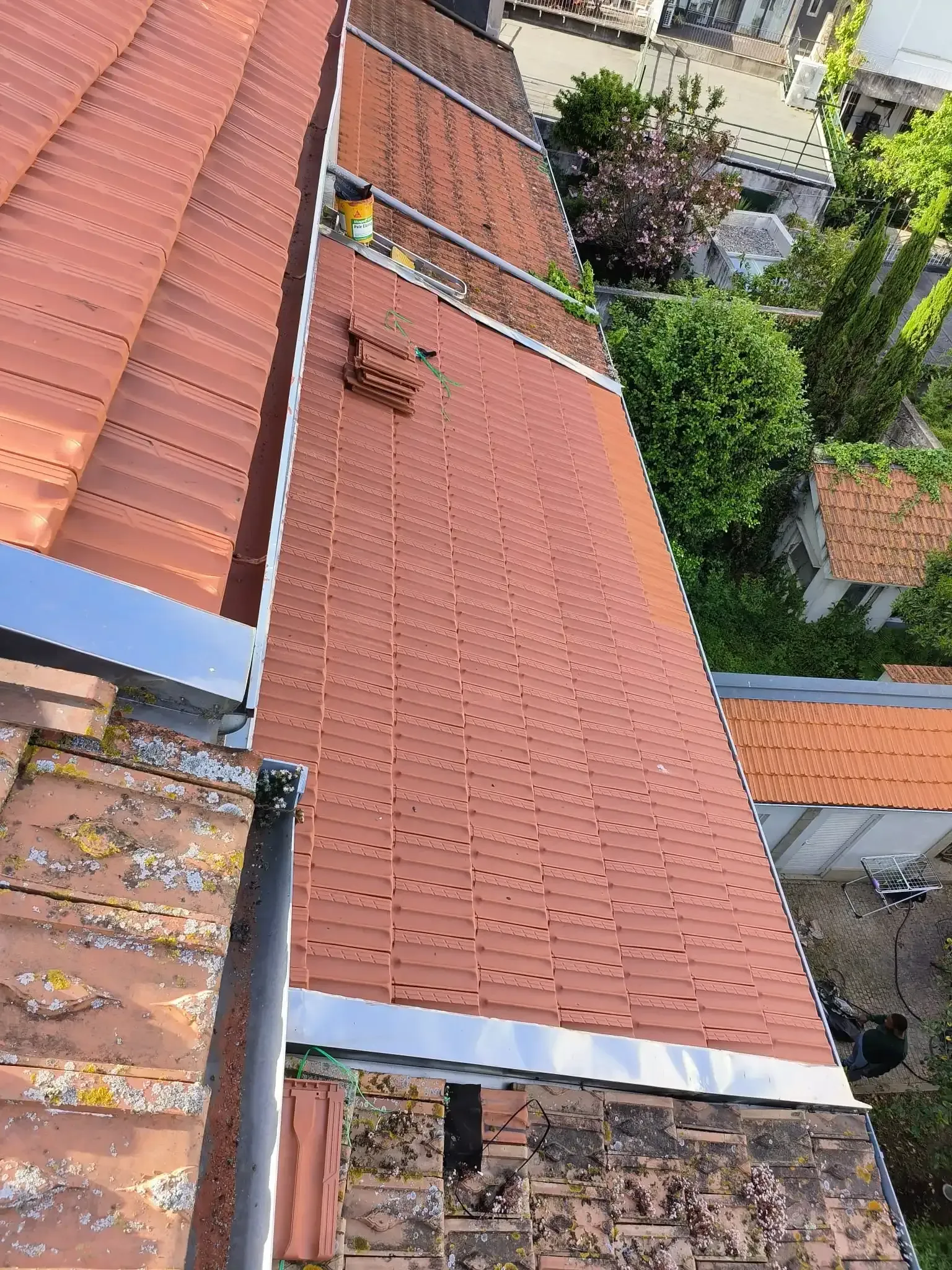 Uma vista aérea de um telhado com telhas vermelhas e uma calha.