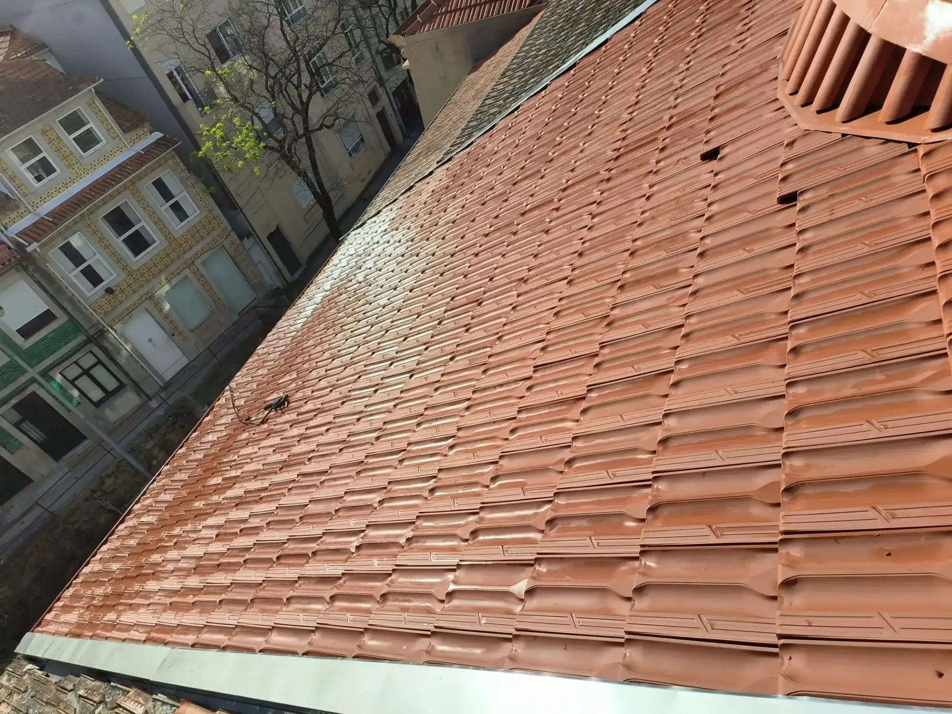 Um telhado de telhas vermelhas com uma chaminé em cima.