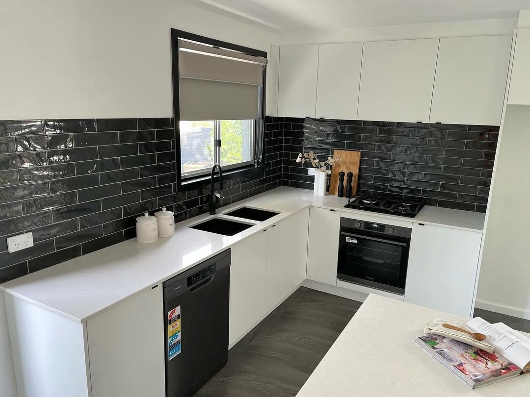 A Kitchen With White Cabinets a Black Dishwasher a Stove and a Window — Canberra Bathroom Solutions in Woden, ACT