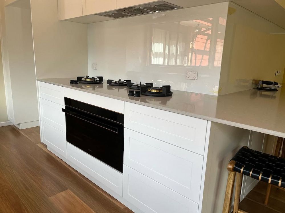 A Kitchen With White Cabinets and a Black Oven — Canberra Bathroom Solutions in Ngunnawal, ACT