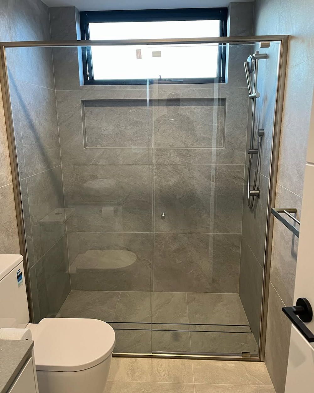 A Toilet is Sitting in a Small Bathroom Next to a Door — Canberra Bathroom Solutions in Ngunnawal, ACT