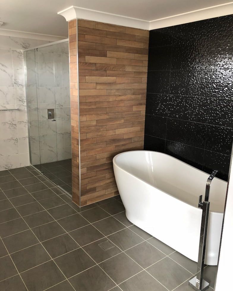 Modern Bathroom With Freestanding White Tub Against a Black Textured Wall